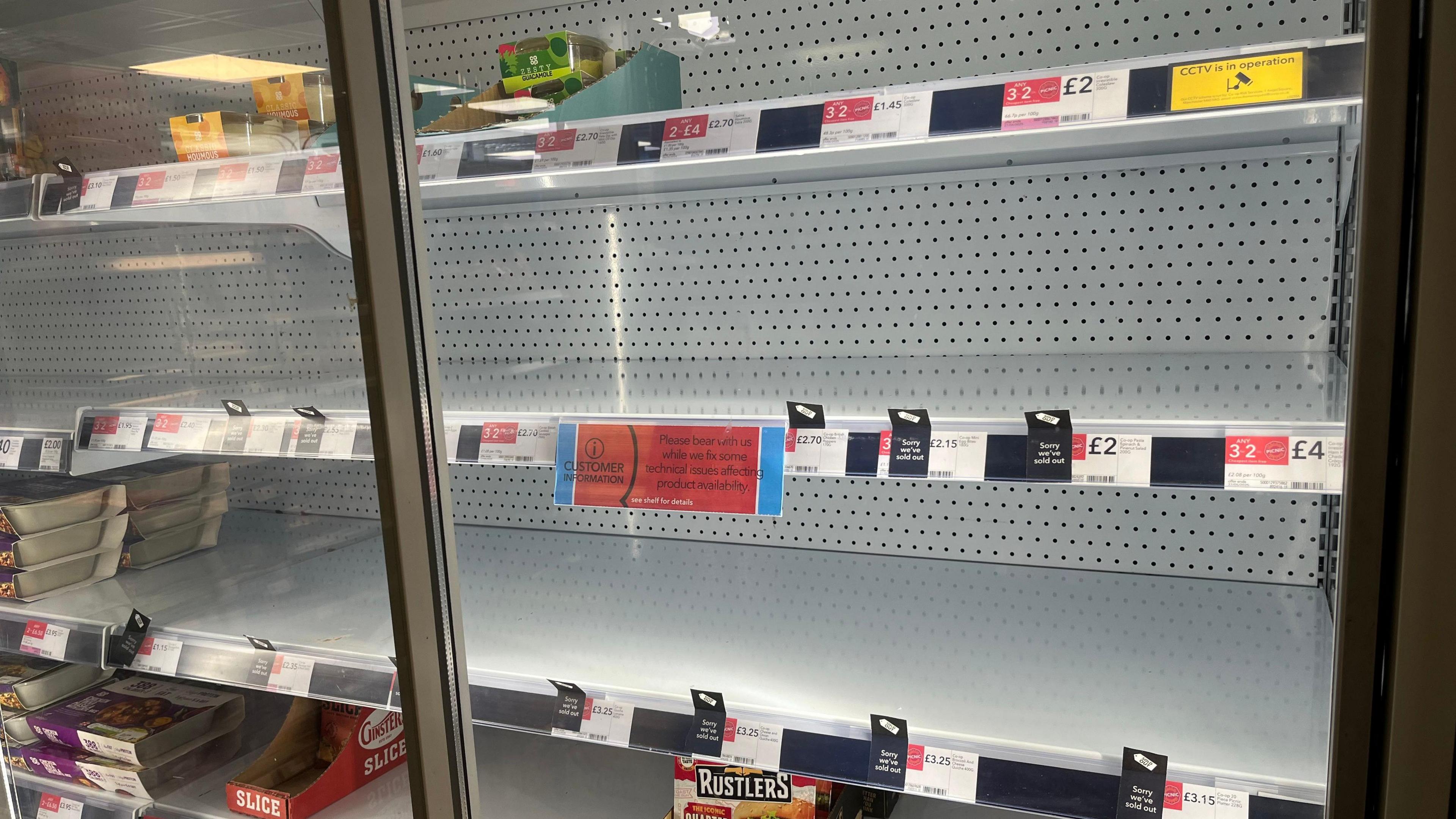 A chiller cabinet at the Co-Op in Loose Road, Maidstone, is left half empty with signs apologising for items not being in stock