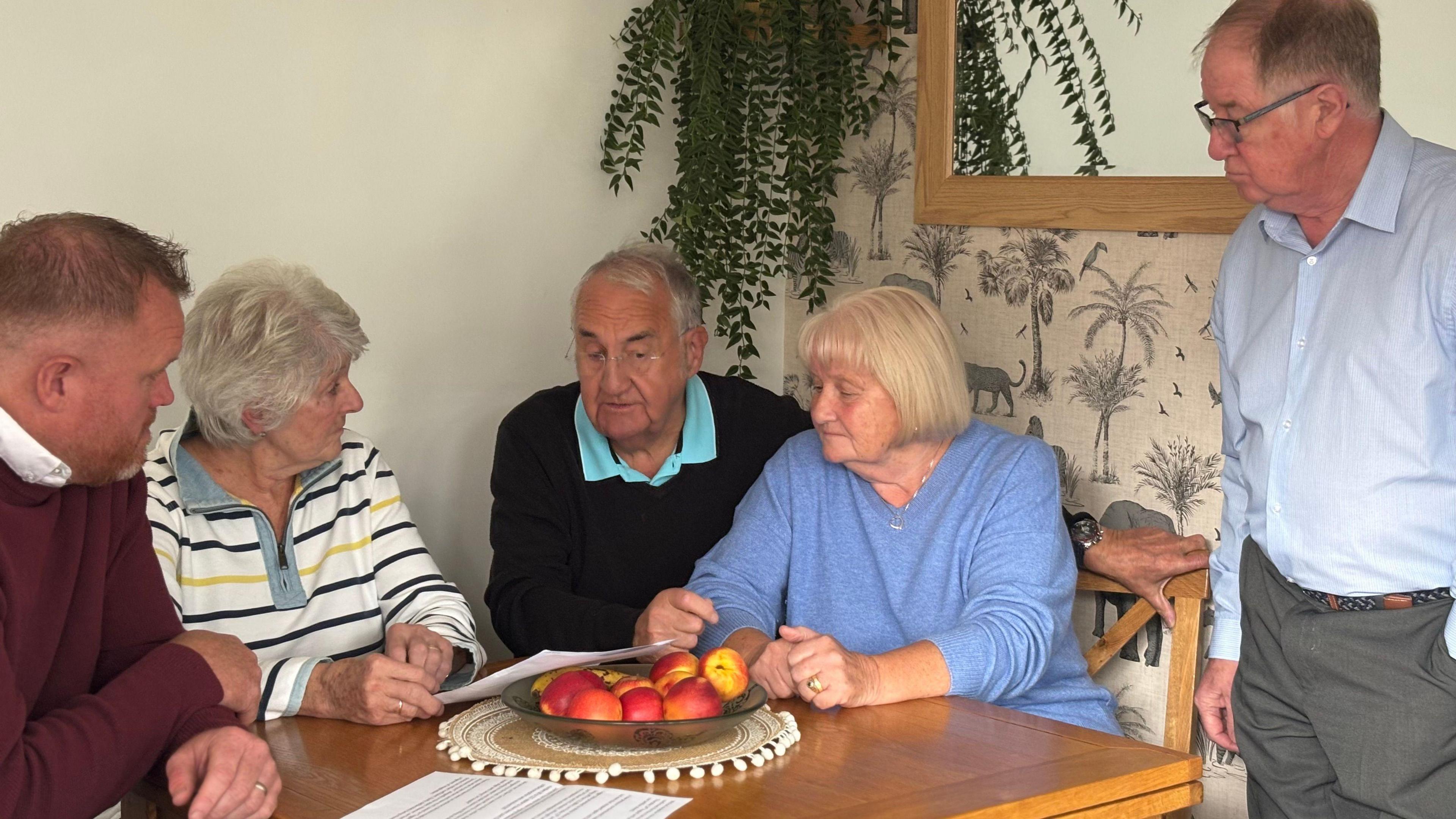 Grŵp o gymdogion yn cynnal cyfarfod wrth fwrdd