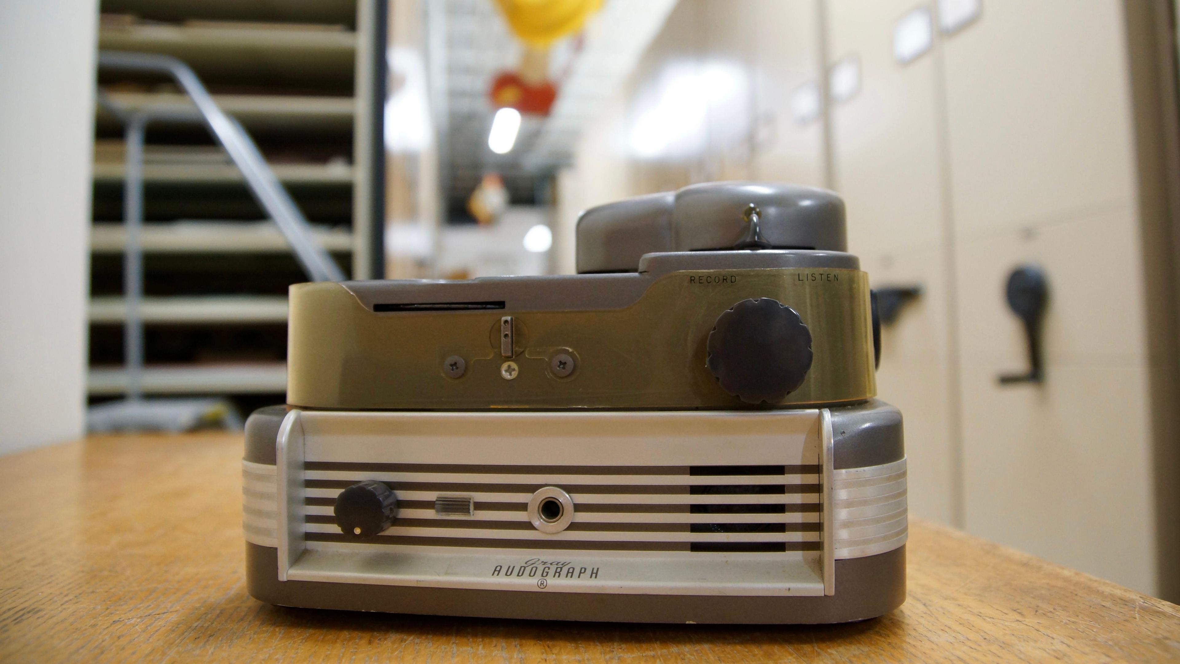 An audio recording device on a table, with a handset and dials