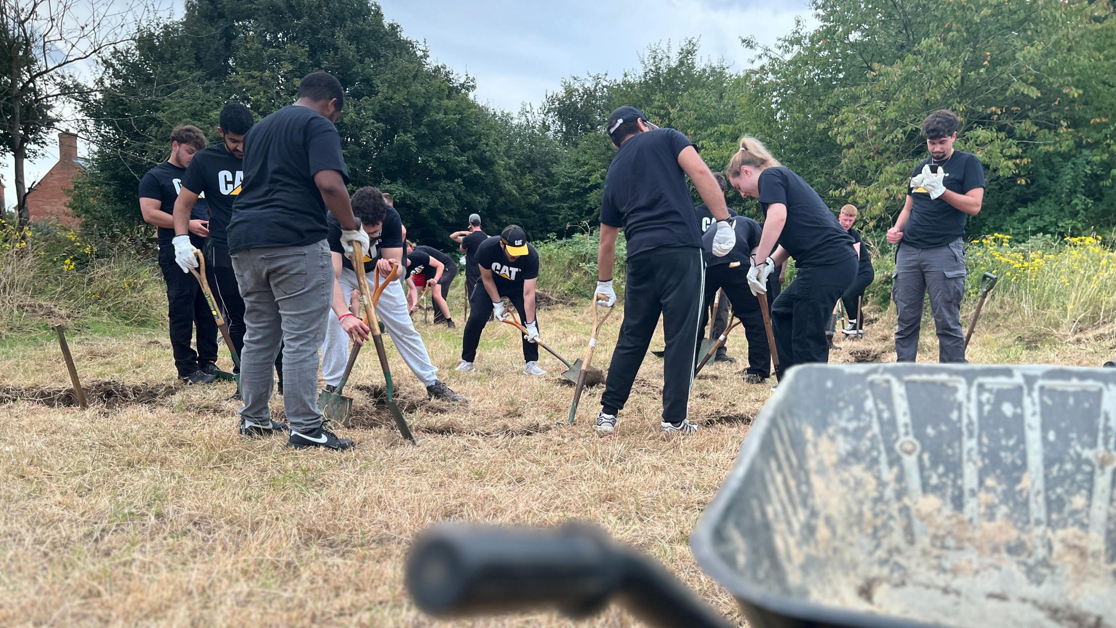 Group of volunteers in black t-shirts digging in a field