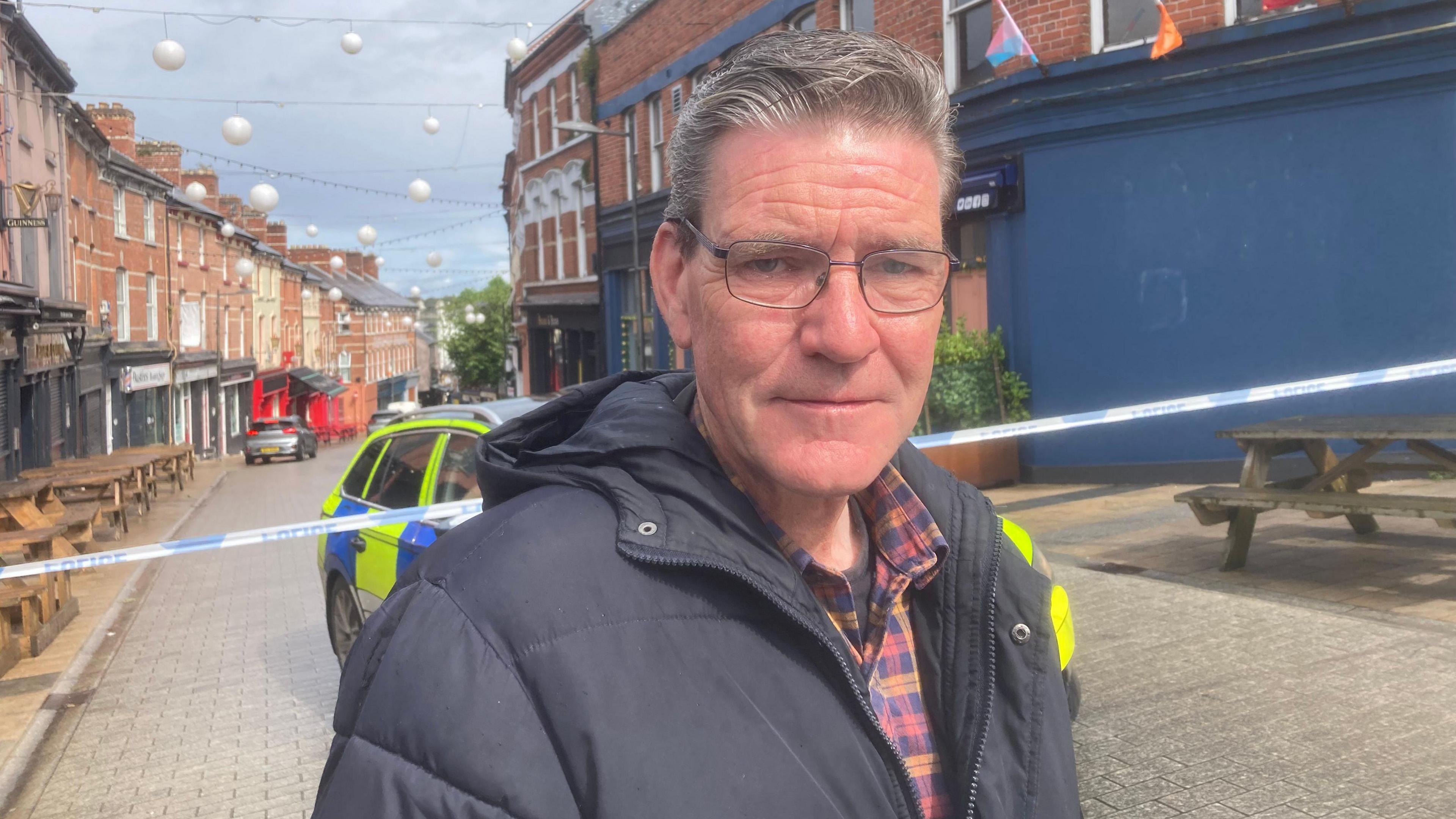 SDLP councillor John Boyle stands in front of the police cordon where a woman died following a fire in a flat in Londonderry