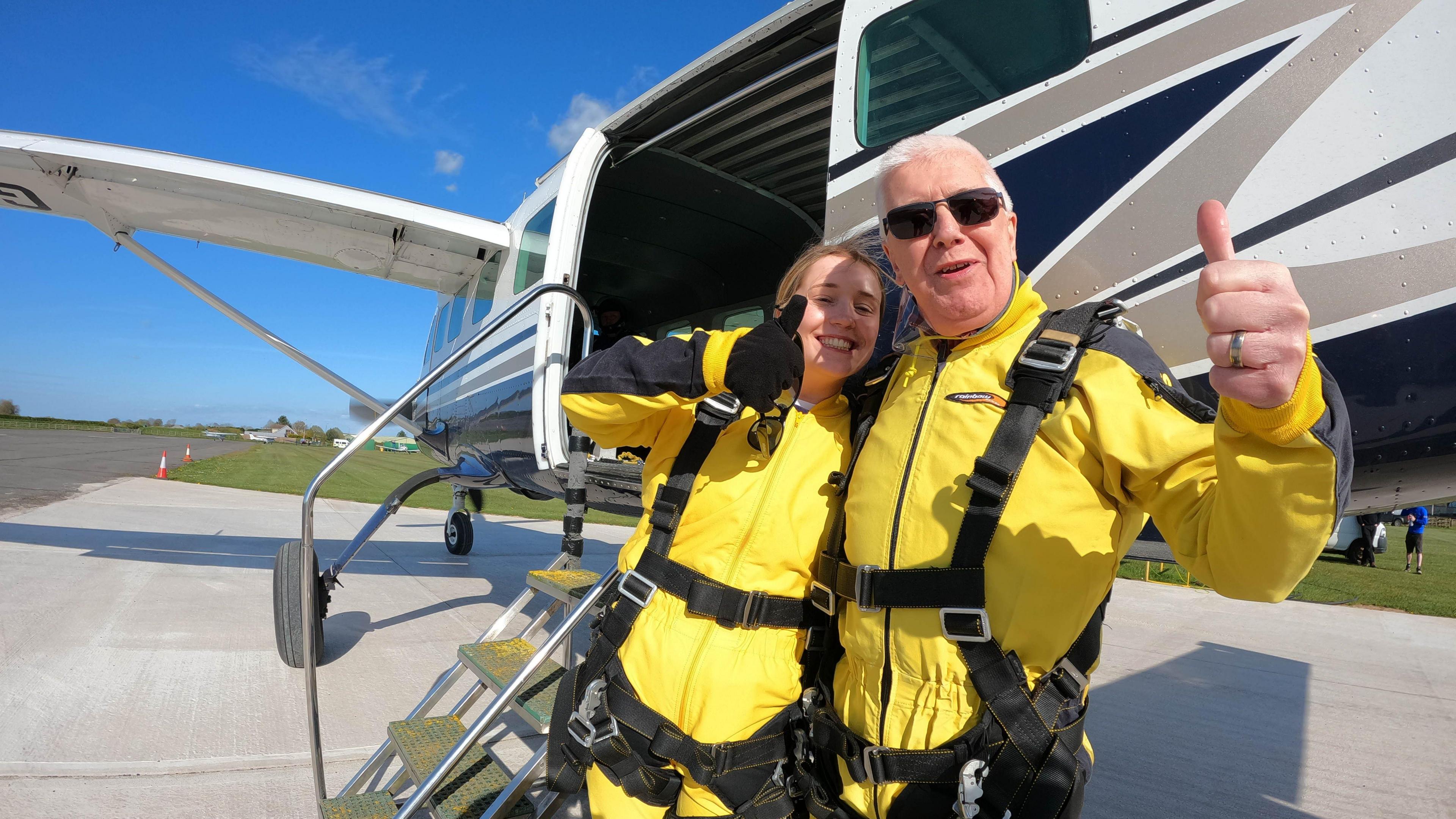 Freya and her grandfather standing in front of a plane