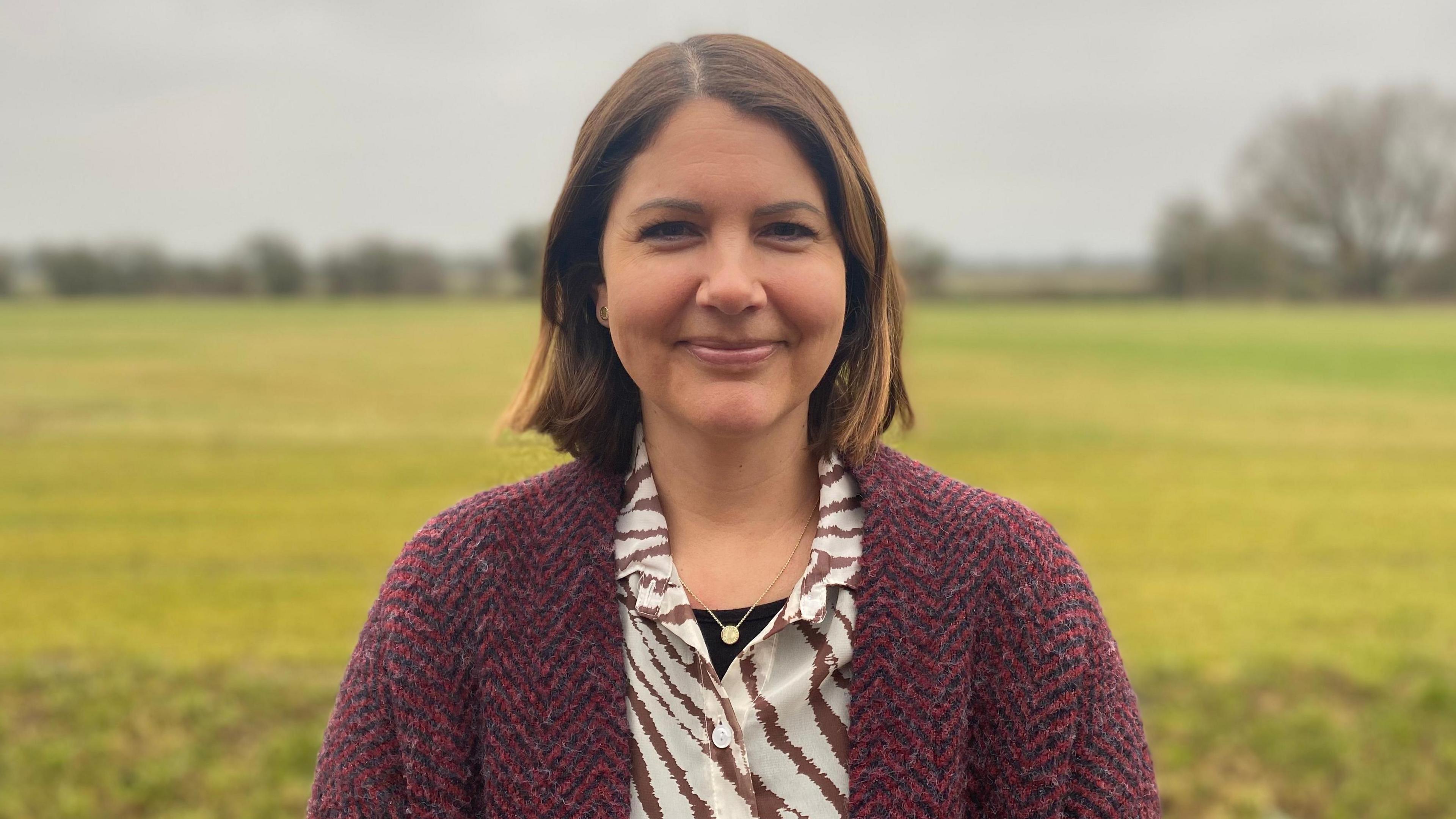 A head and shoulders of woman stood outside in countryside