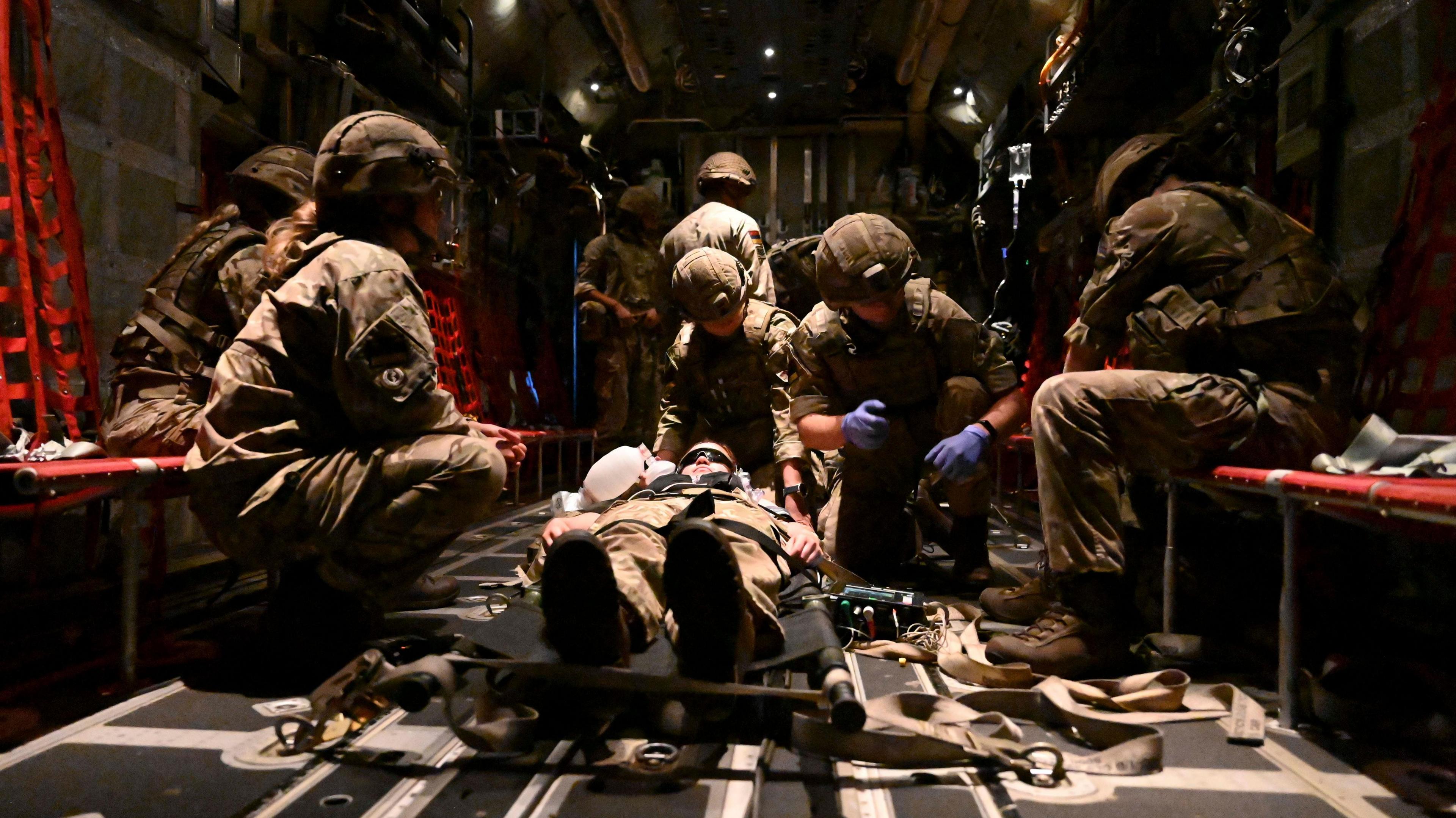 Another medical simulation is carried out on a larger aircraft. A fake casualty lies on a stretcher in the middle of the aircraft while military personnel sit around them and attend to them.