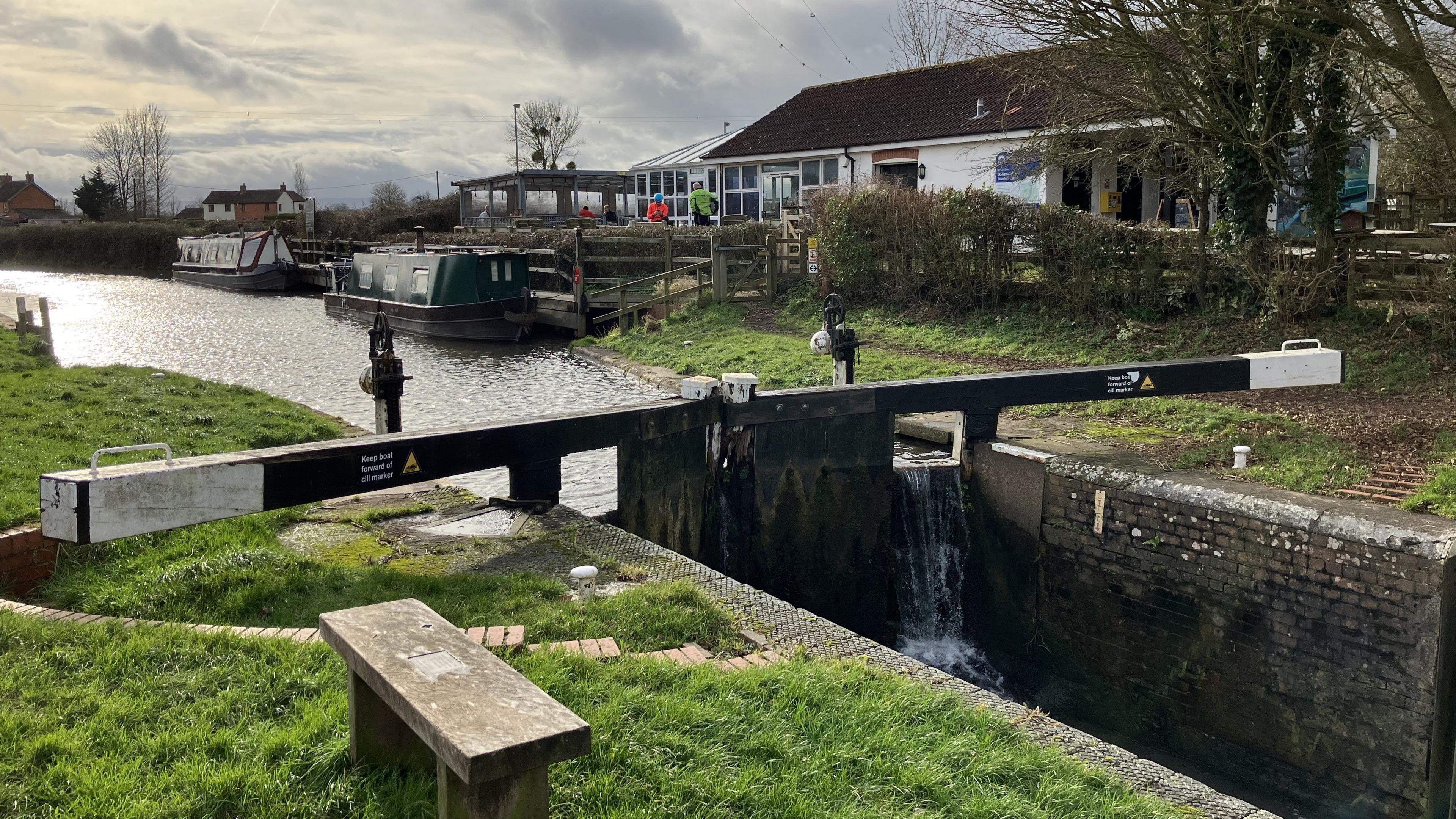 A canal lock with two barges moored in the background