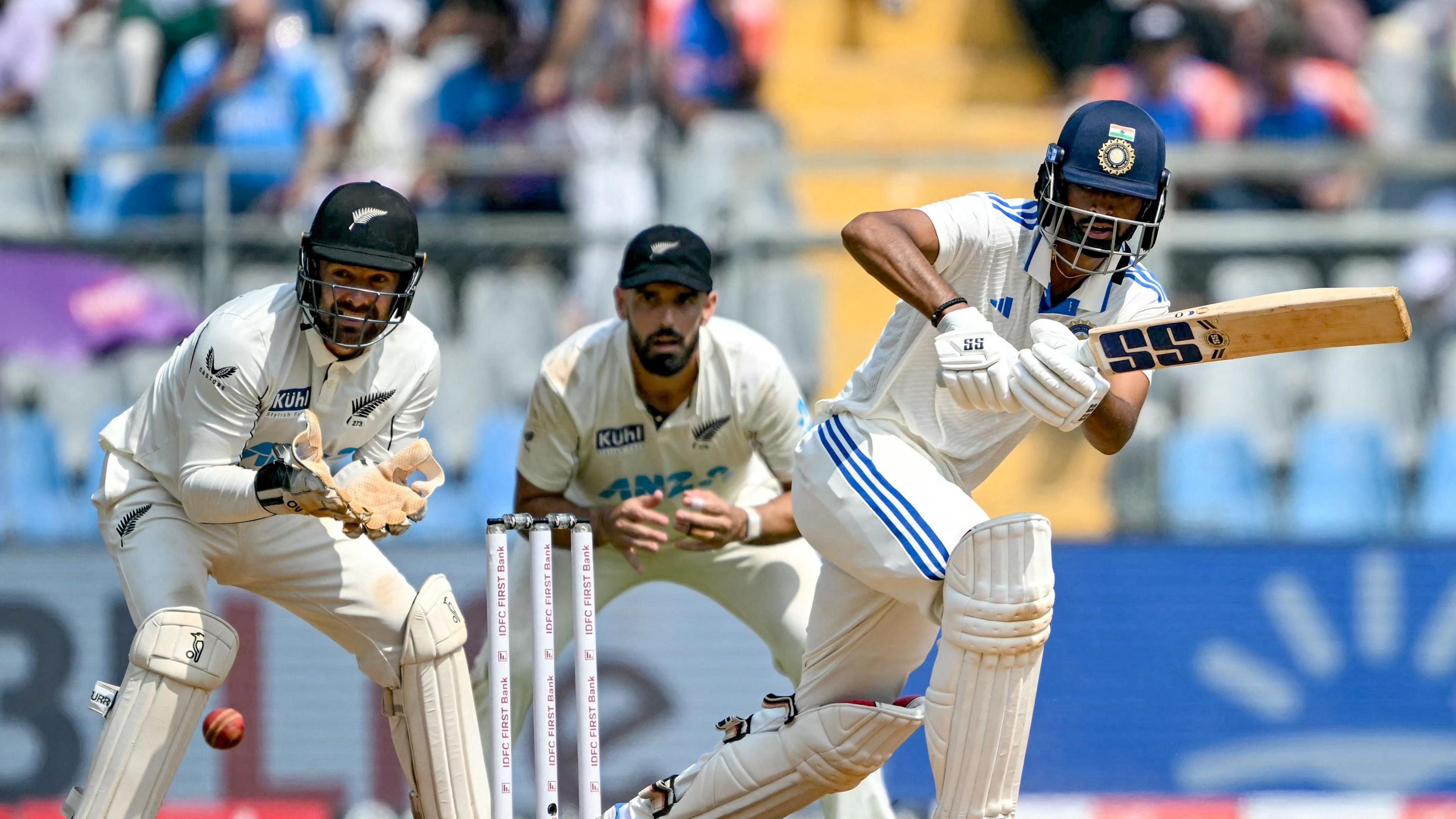 India's Washington Sundar plays a shot, watched by New Zealand wicketkeeper Tom Blundell and fielder Daryl Mitchell, in a Test in 2024