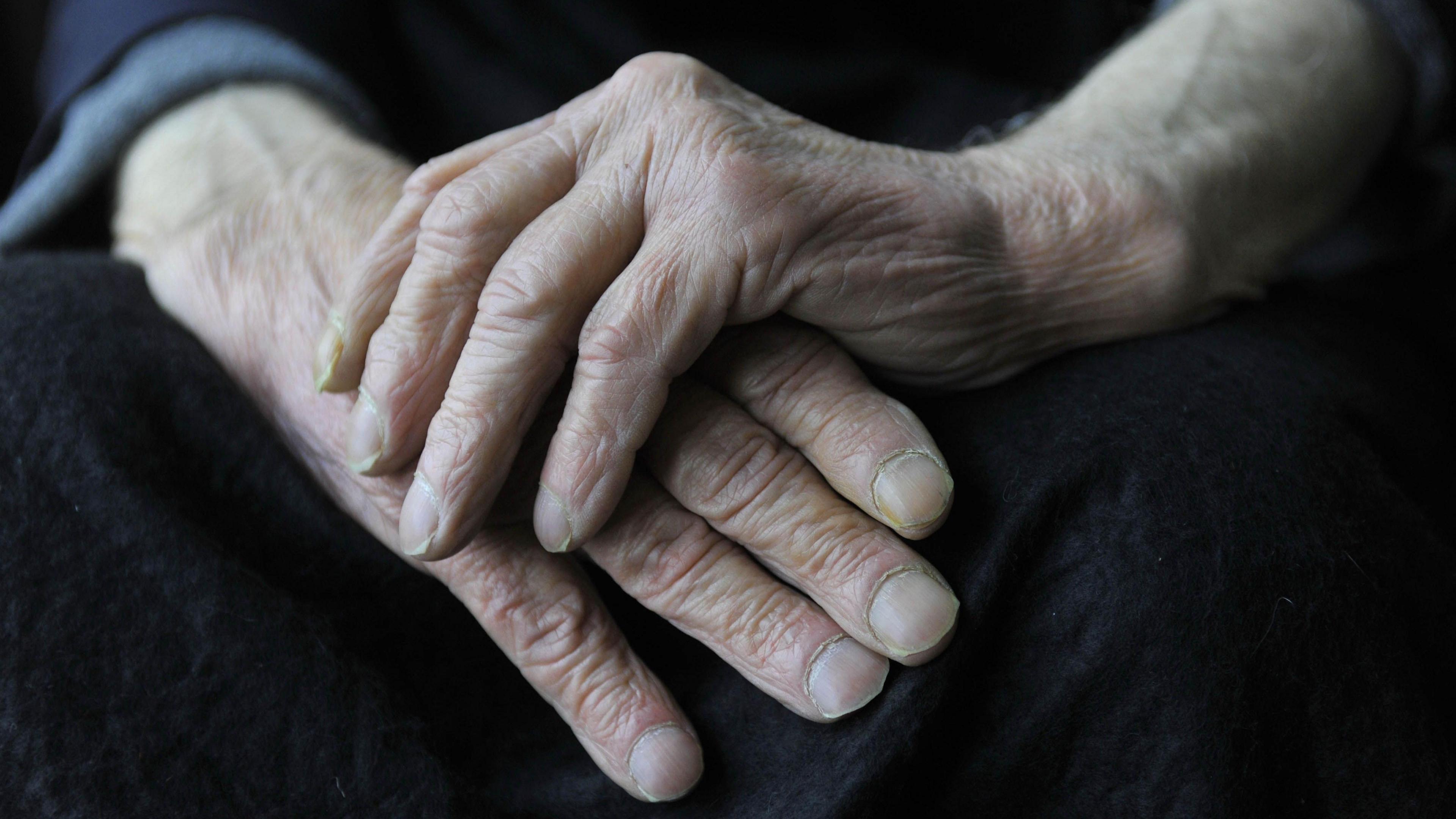 A close up of an elderly man's hands resting in one another.