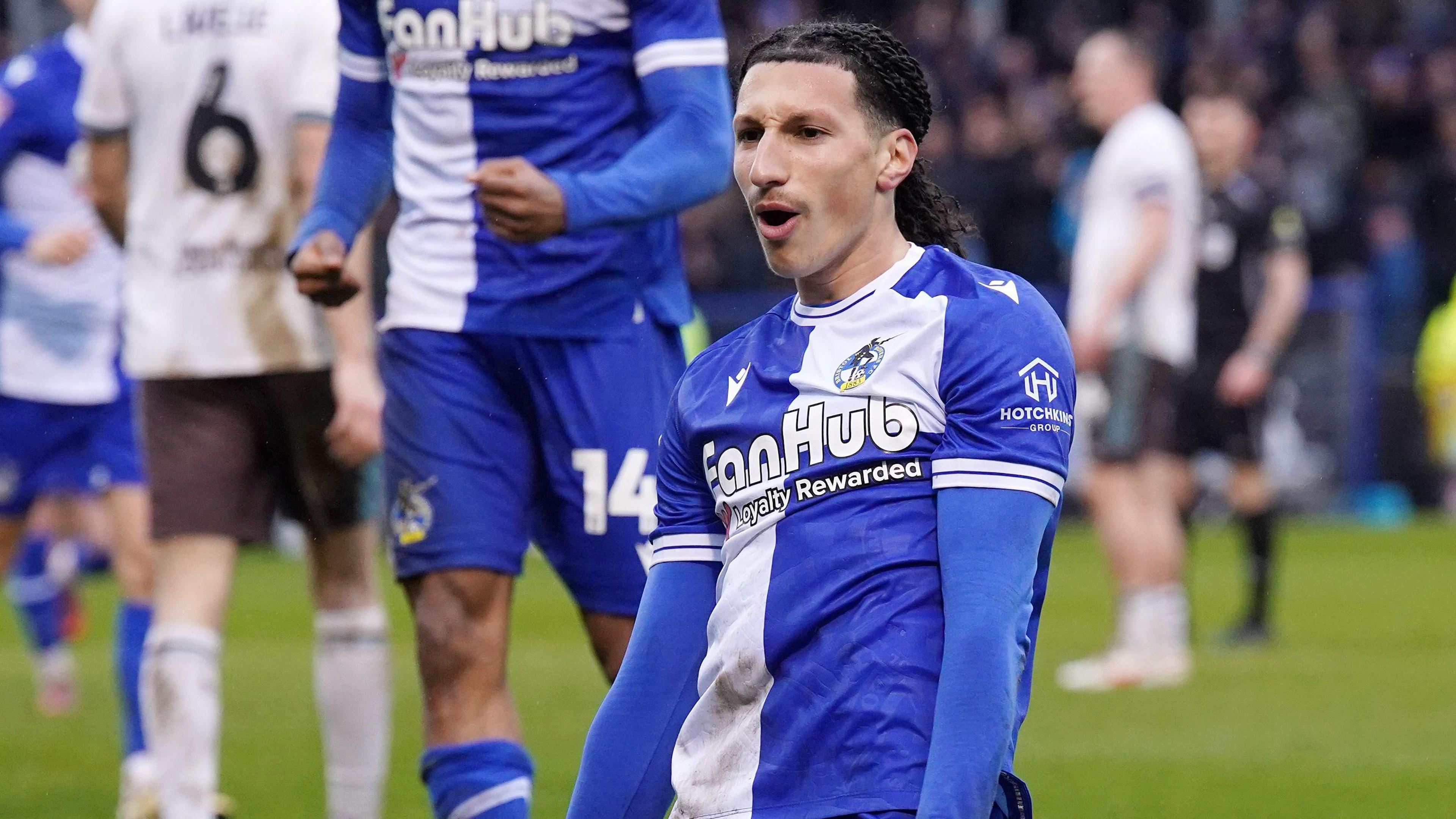 Yusuf Akhamrich slides on his knees with his hands by his side after scoring a goal