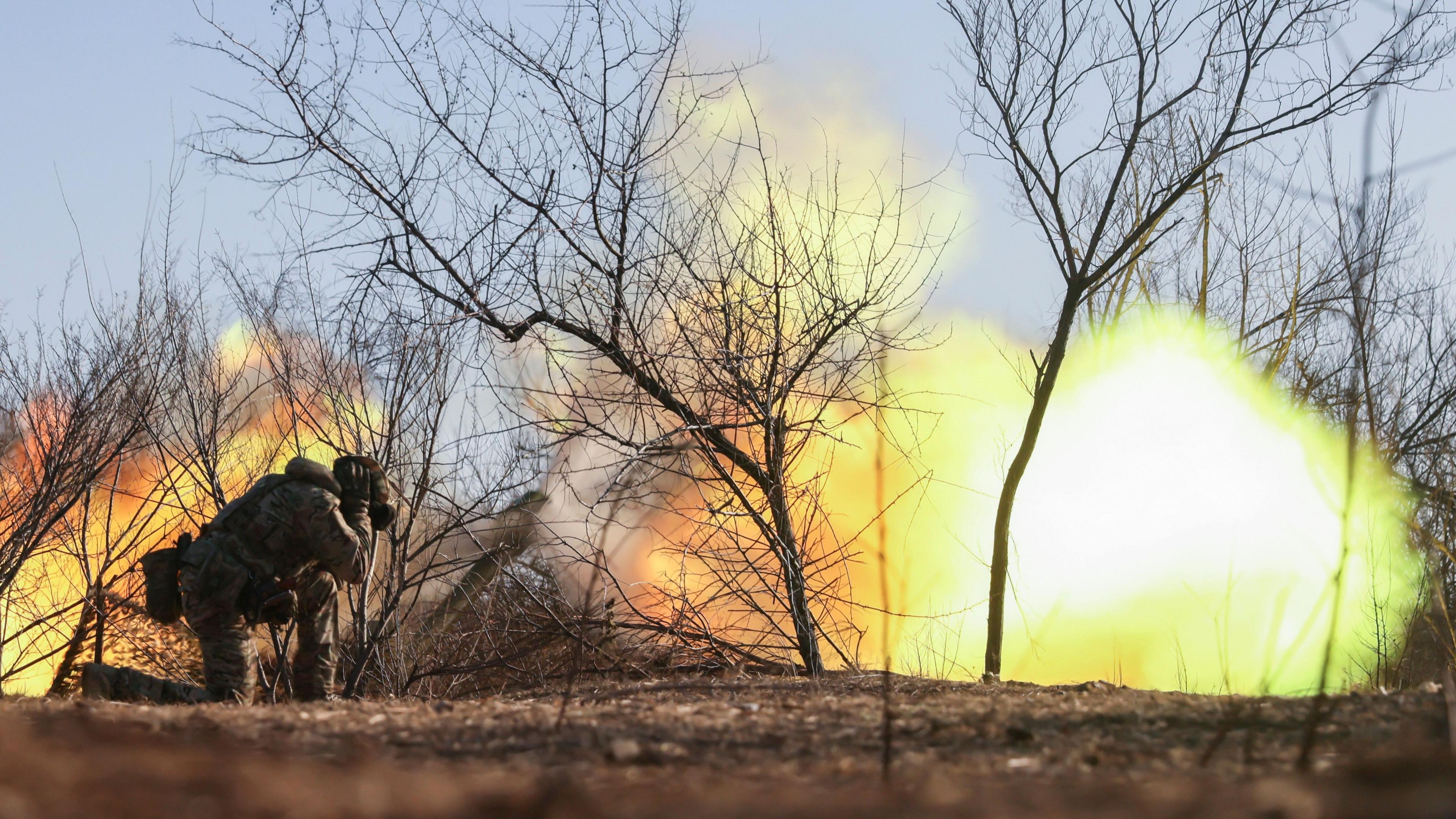 A Ukrainian soldier covers his ears as a howitzer fires in the Zaporizhzhia region of Ukraine