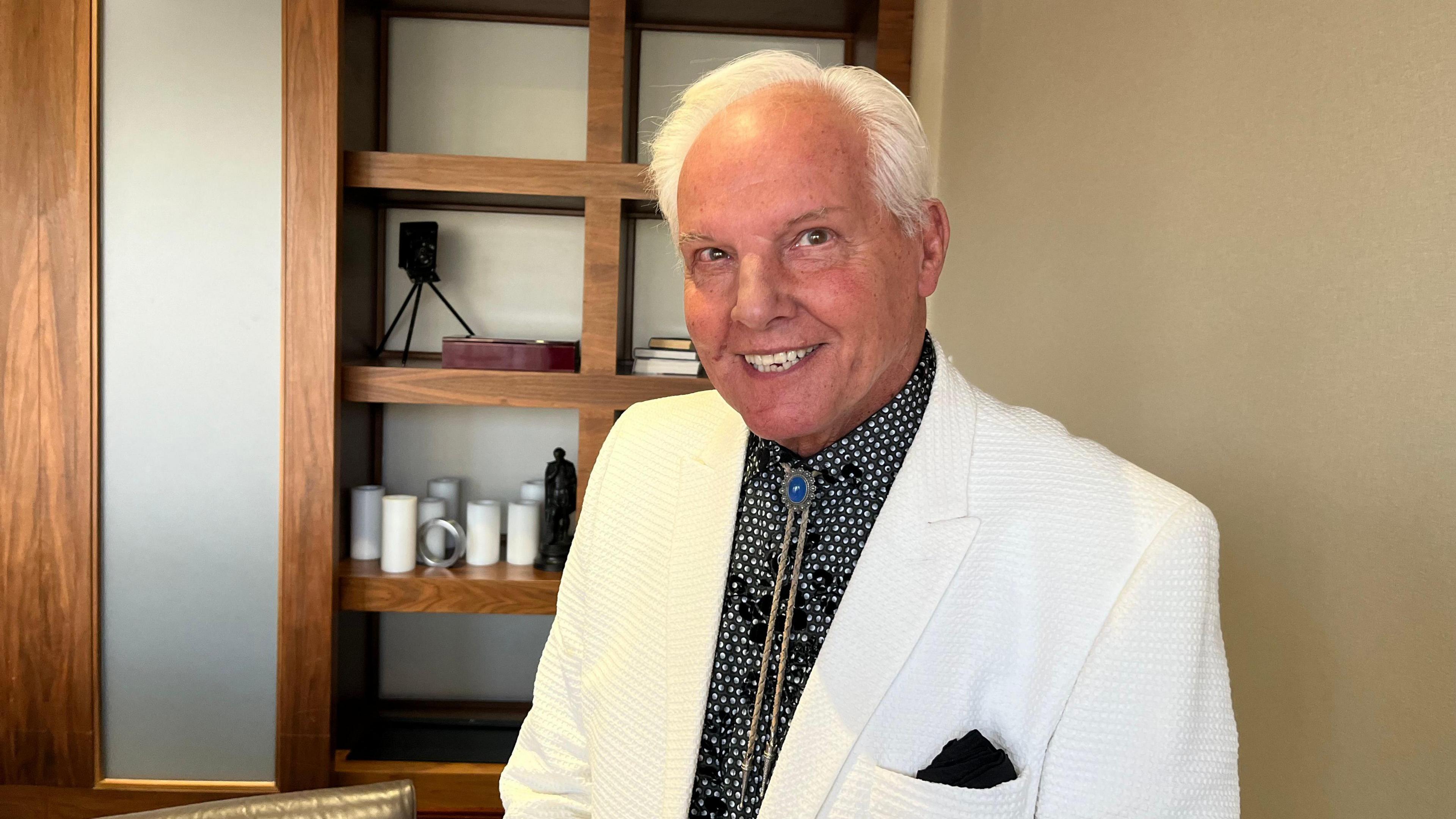 Jess Conrad wearing a white suit with a black shirt.