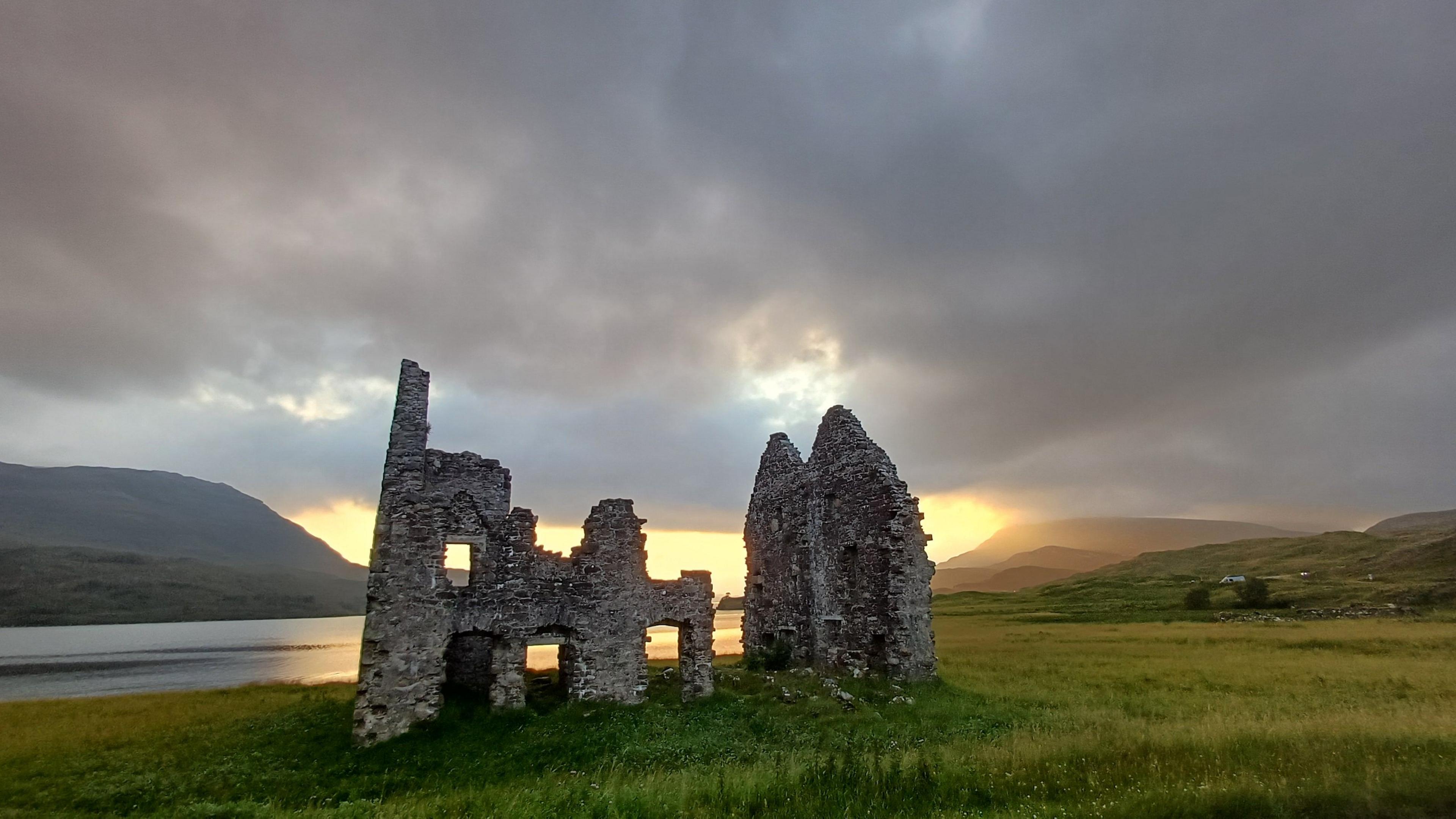 Sunset image of the ruins of a castle on the edge of Loch Assynt