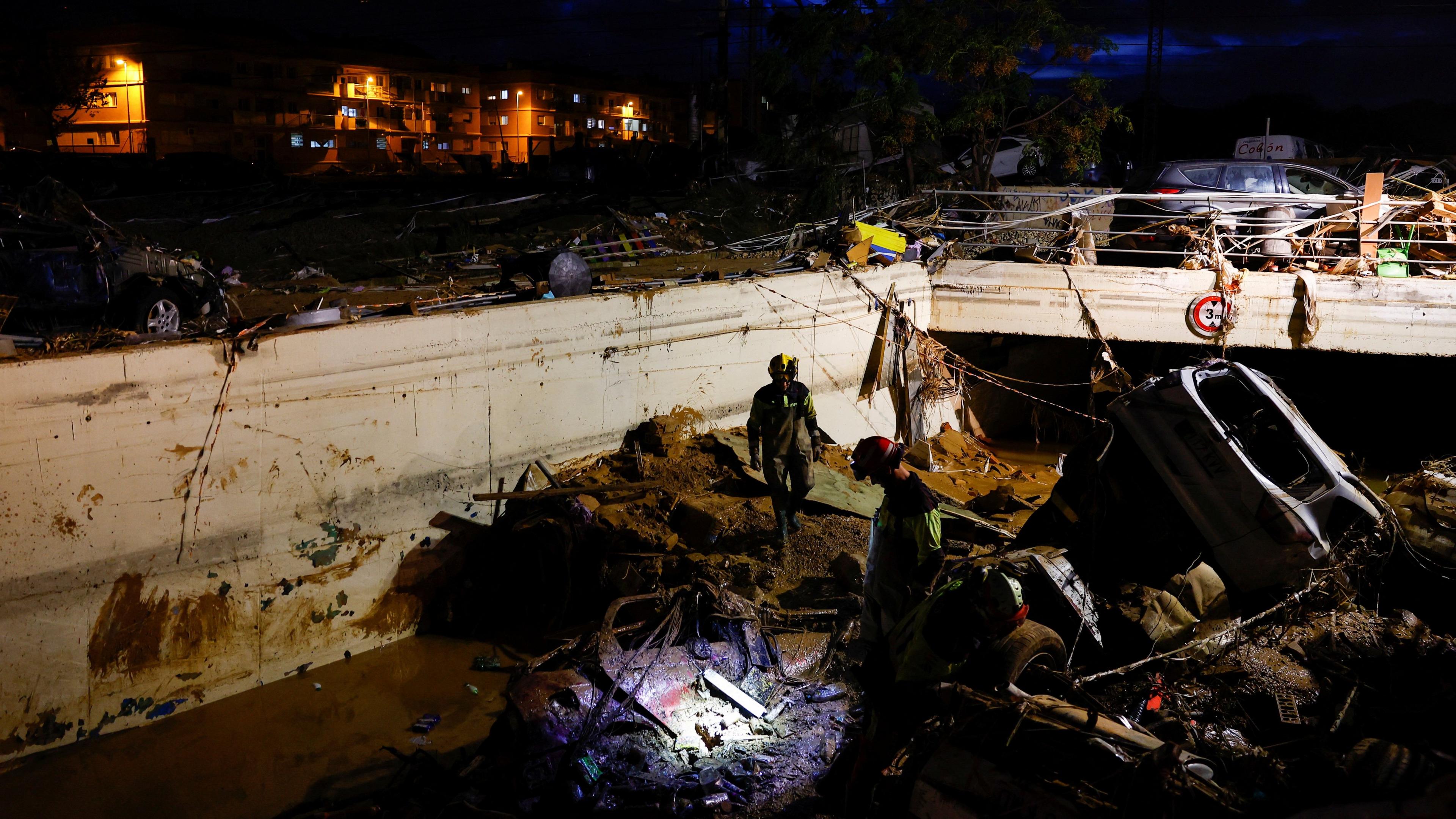 Rescuers surrounded by debris search in one spot by a tunnel