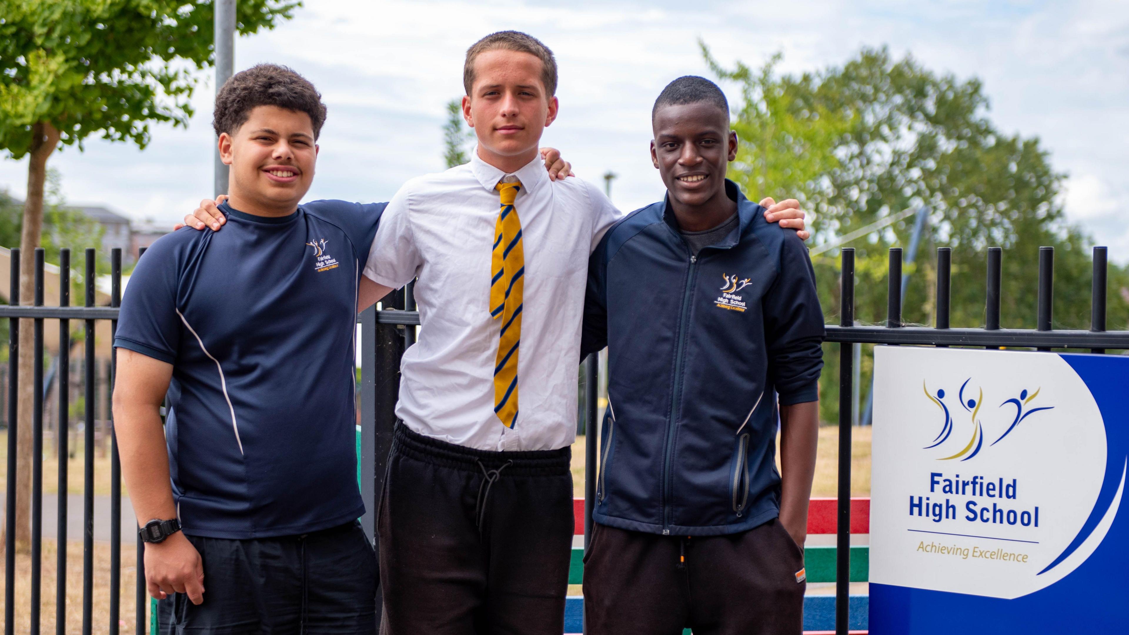 Three male Fairfield School pupils link arms as they line up for the camera. One of them is wearing a white shirt while the other two are wearing dark blue sports kits.