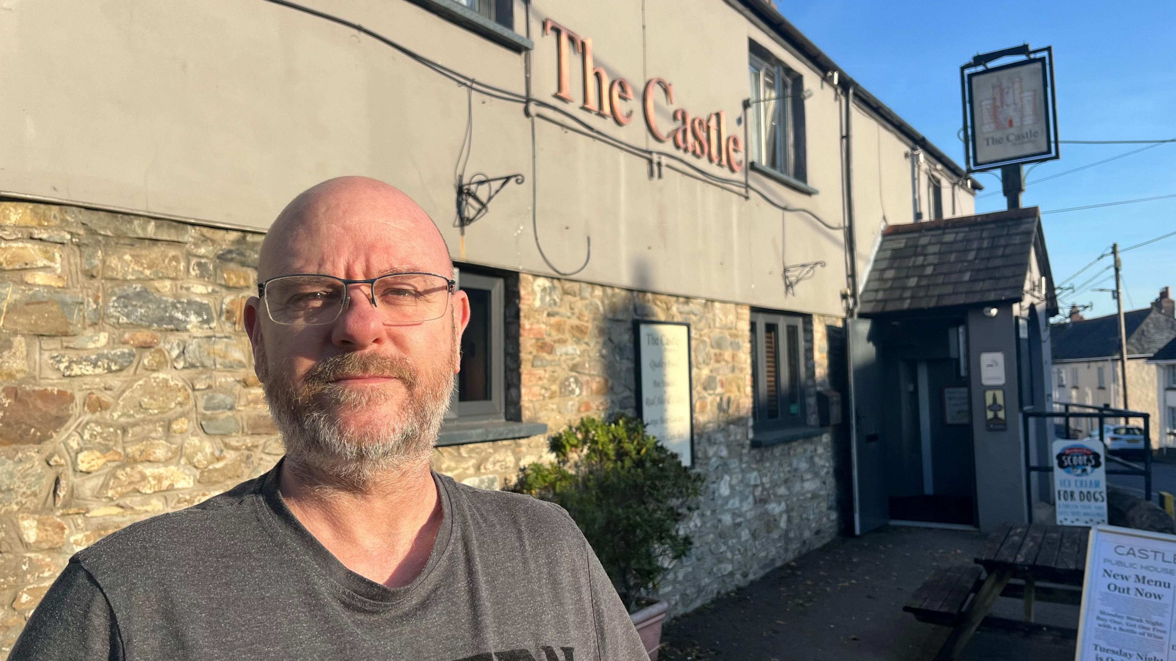 Castle Inn landlord Creighton Kirk in front of his pub wearing a grey T-shirt