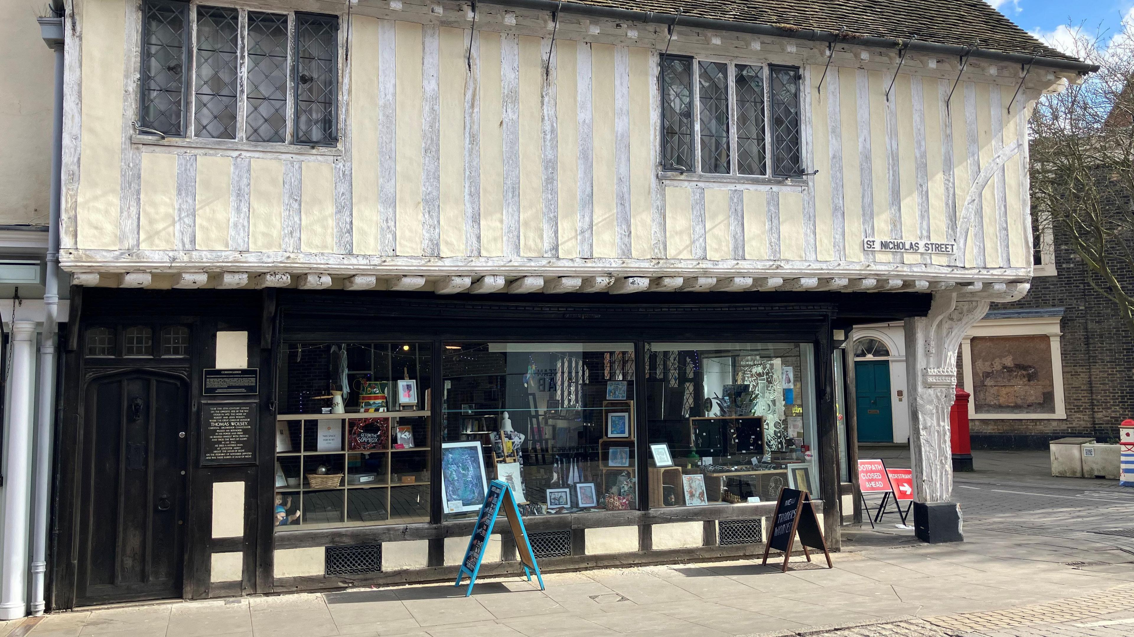 The outside of Curson lodge, a Tudor building with white plastic and wood on the second floor, and a glass windows with art work on the group floor.