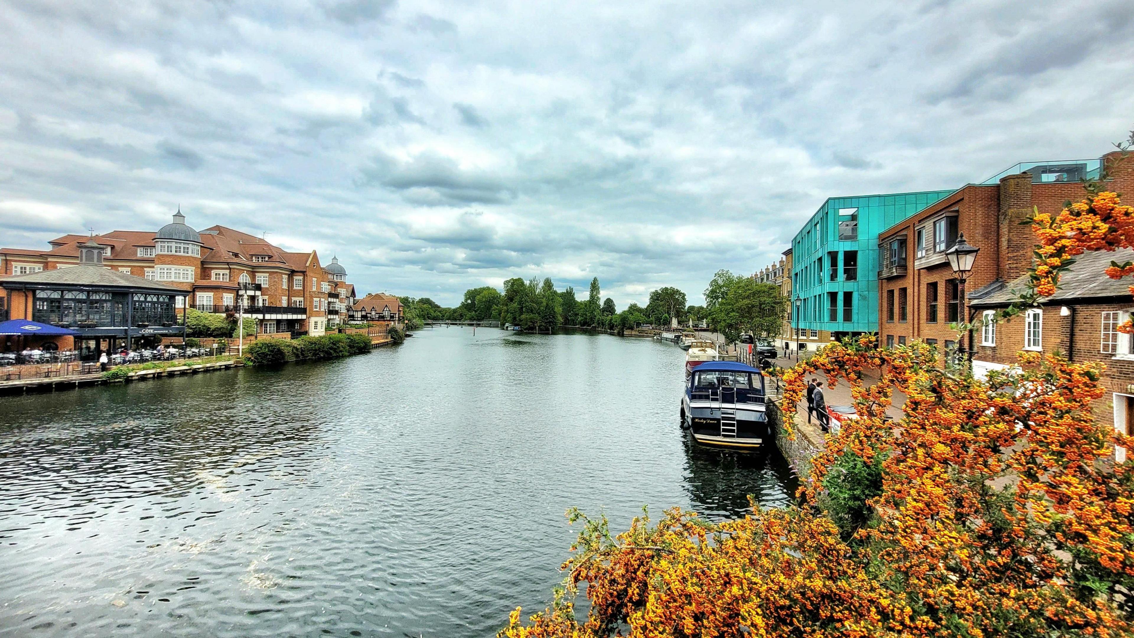 Buildings can be seen either side of a near empty stretch of river under cloudy but bright skies