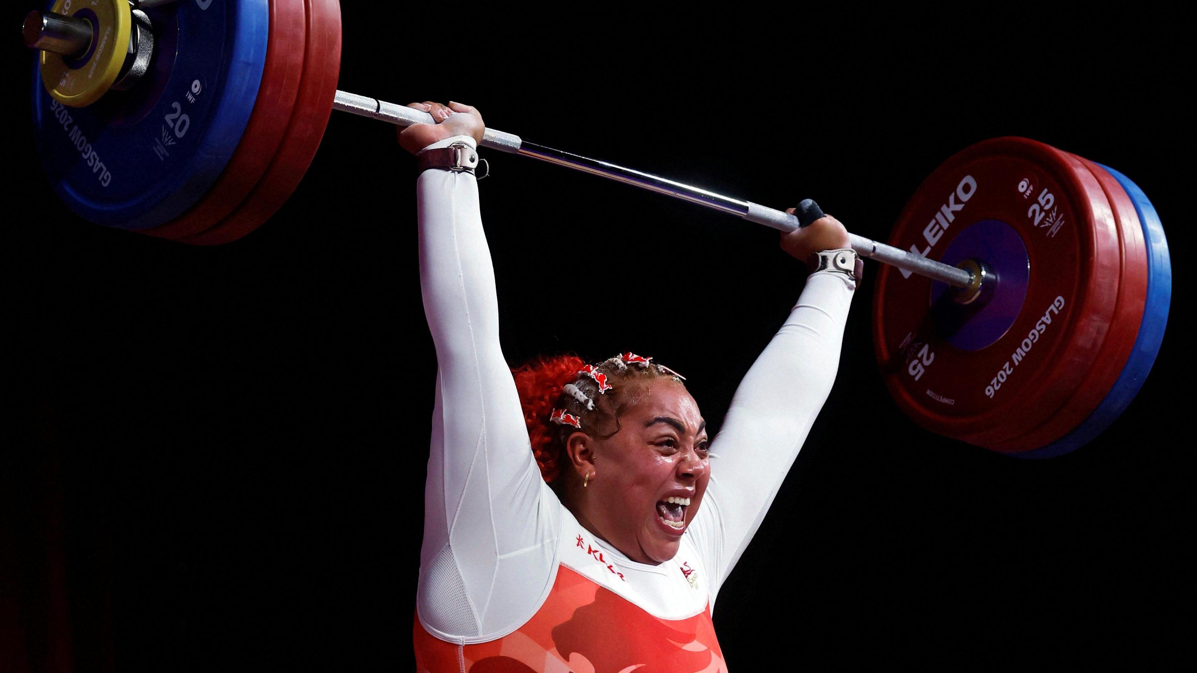 Emily Cambell celebrating while holding a big bar weight