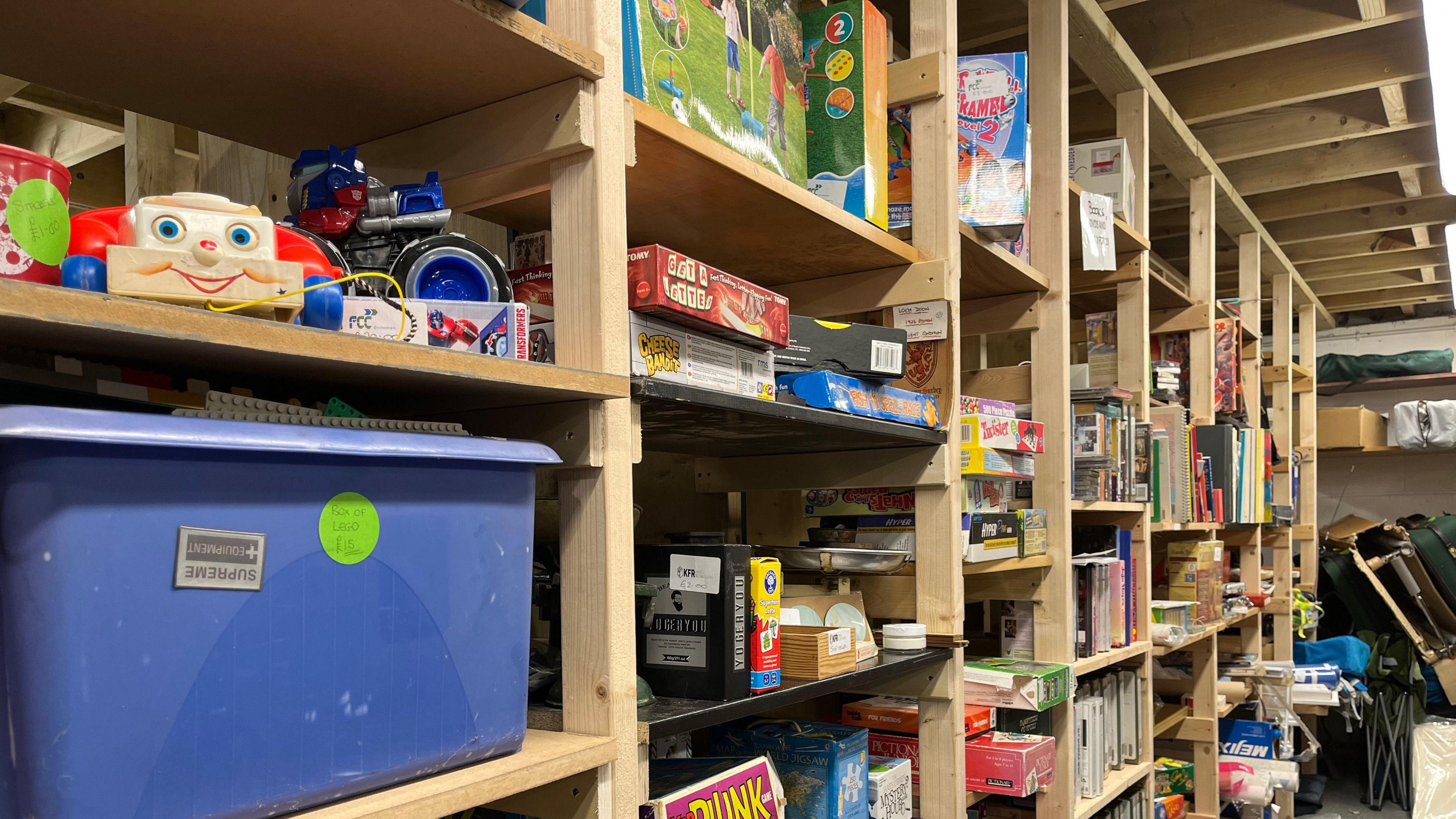 A row of wooden shelves with colourful smaller items: games, toys, books