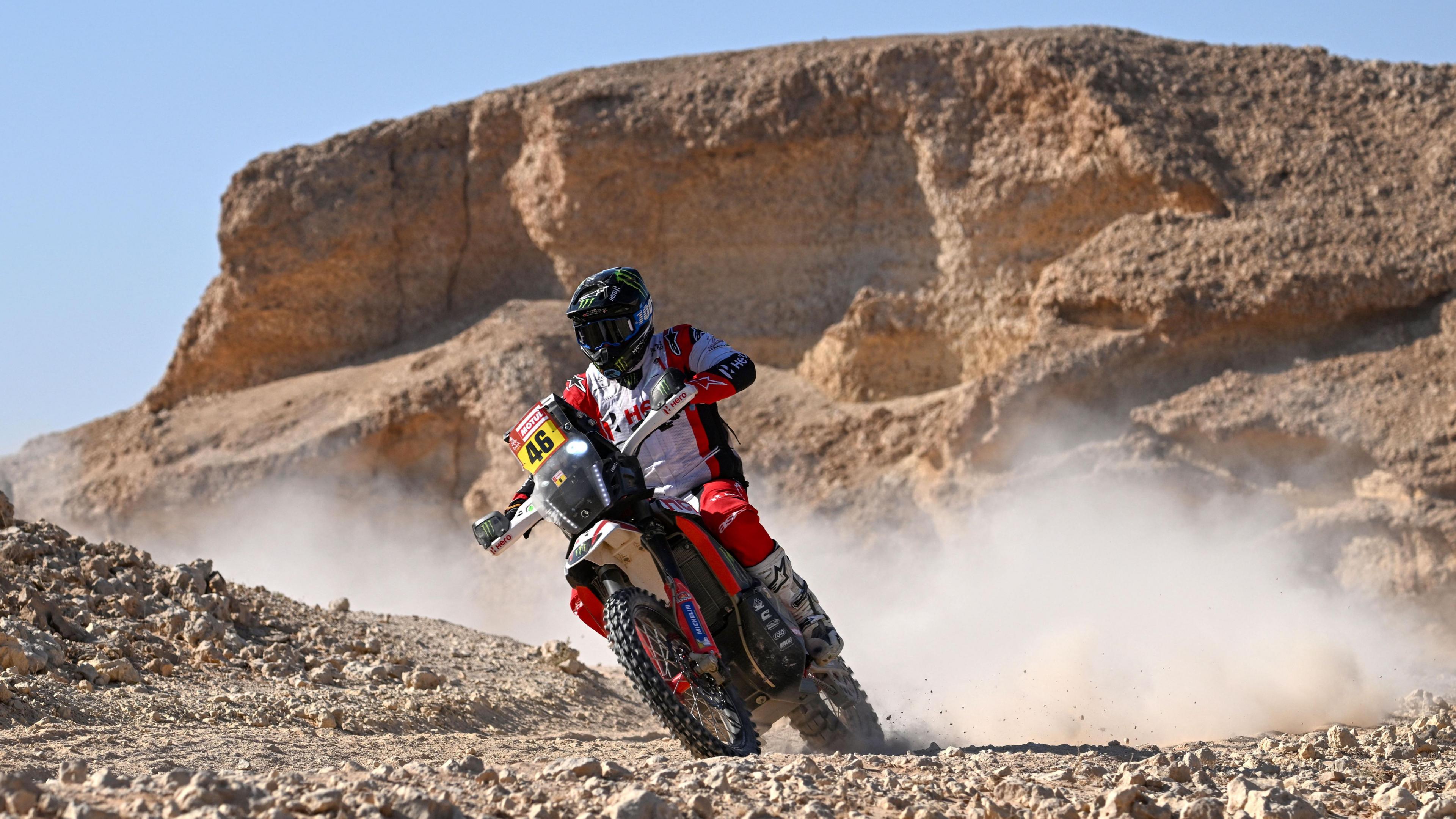 Ross Branch wears white, red and black overalls as he leans to his right while controlling his Hero 450 Rally bike in extreme desert terrain during the 2024 Dakar Rally in Saudi Arabia