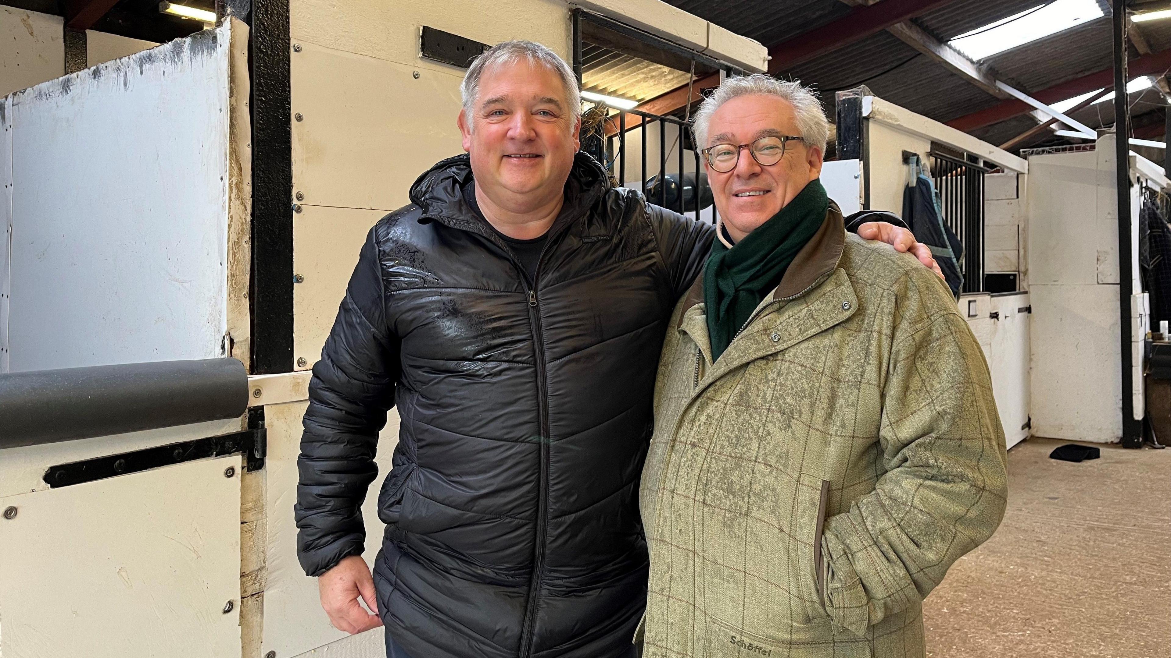 Two men in horse stables