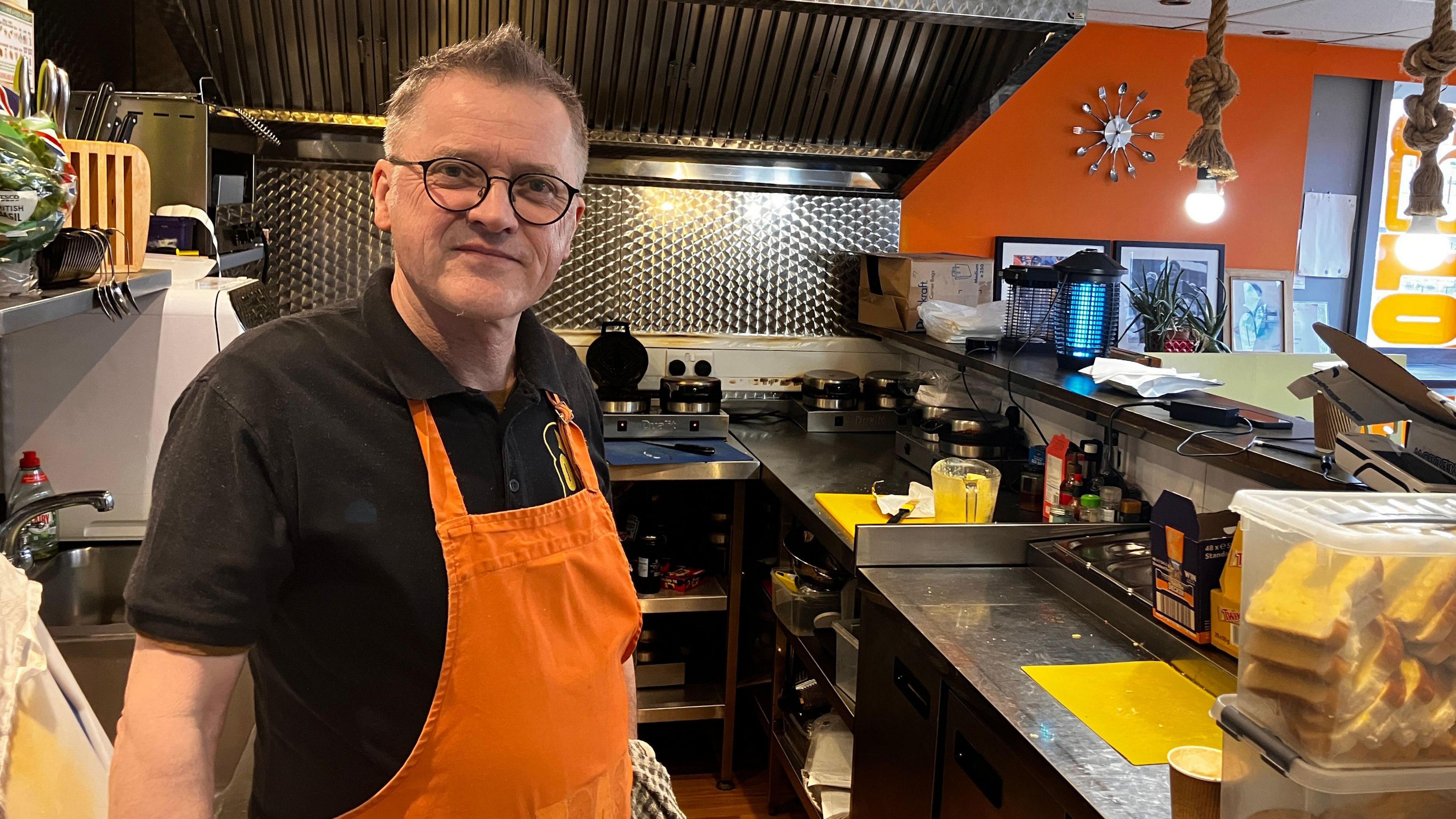 A photo of the owner of on Toast David Purchase standing in front of a counter with kitchen equipment n the background