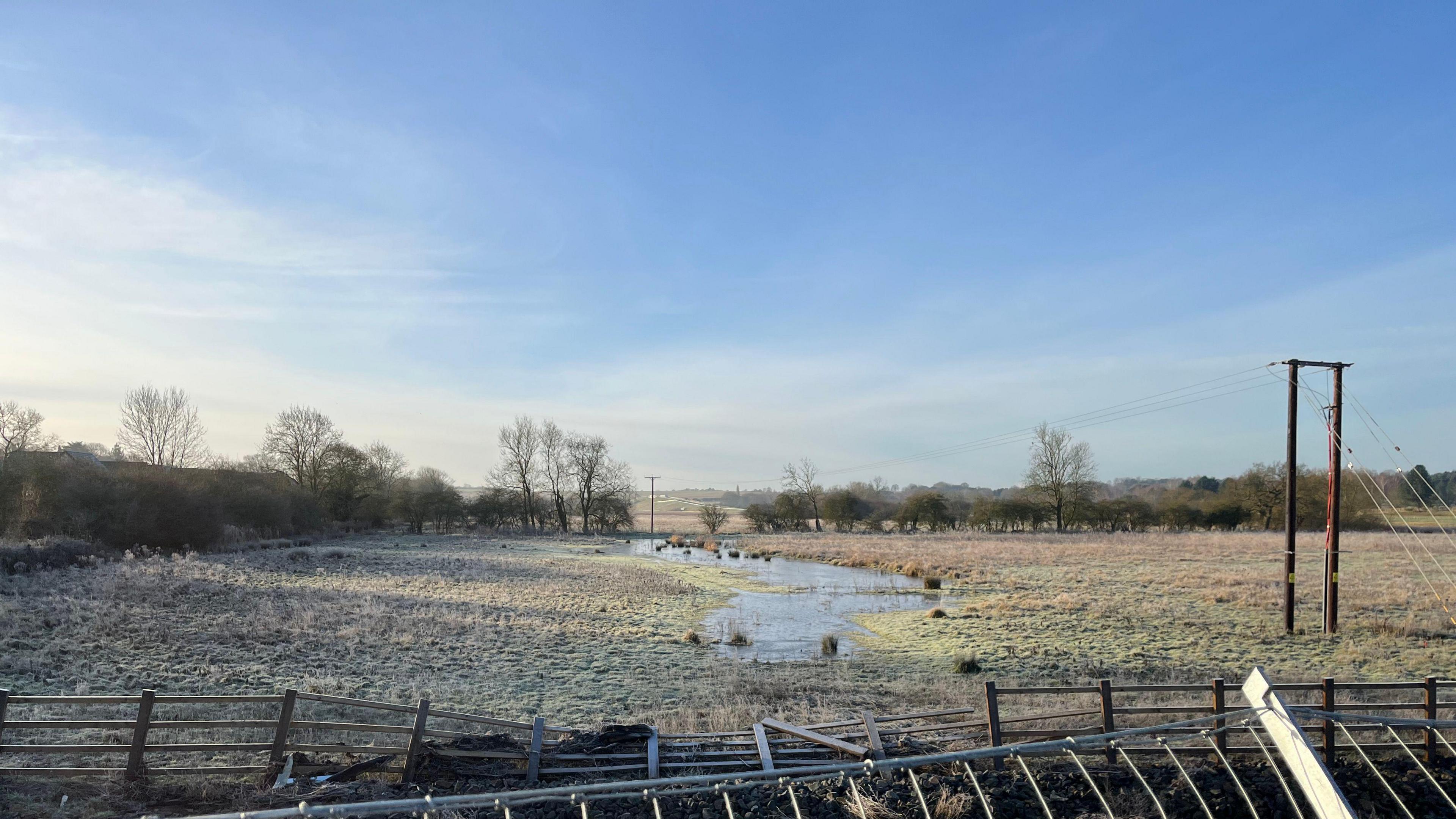 A large open frosty field with a small amount of flooding in the middle. 