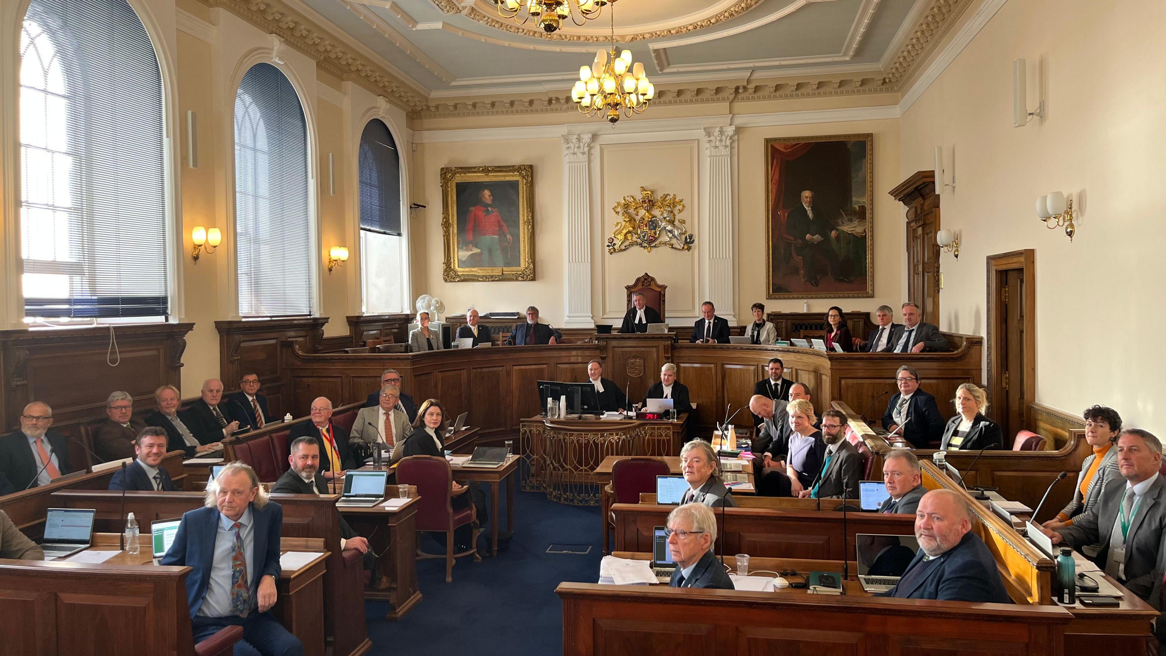 A group of people sitting wearing suits and formal wear in Guernsey's Royal Court. 