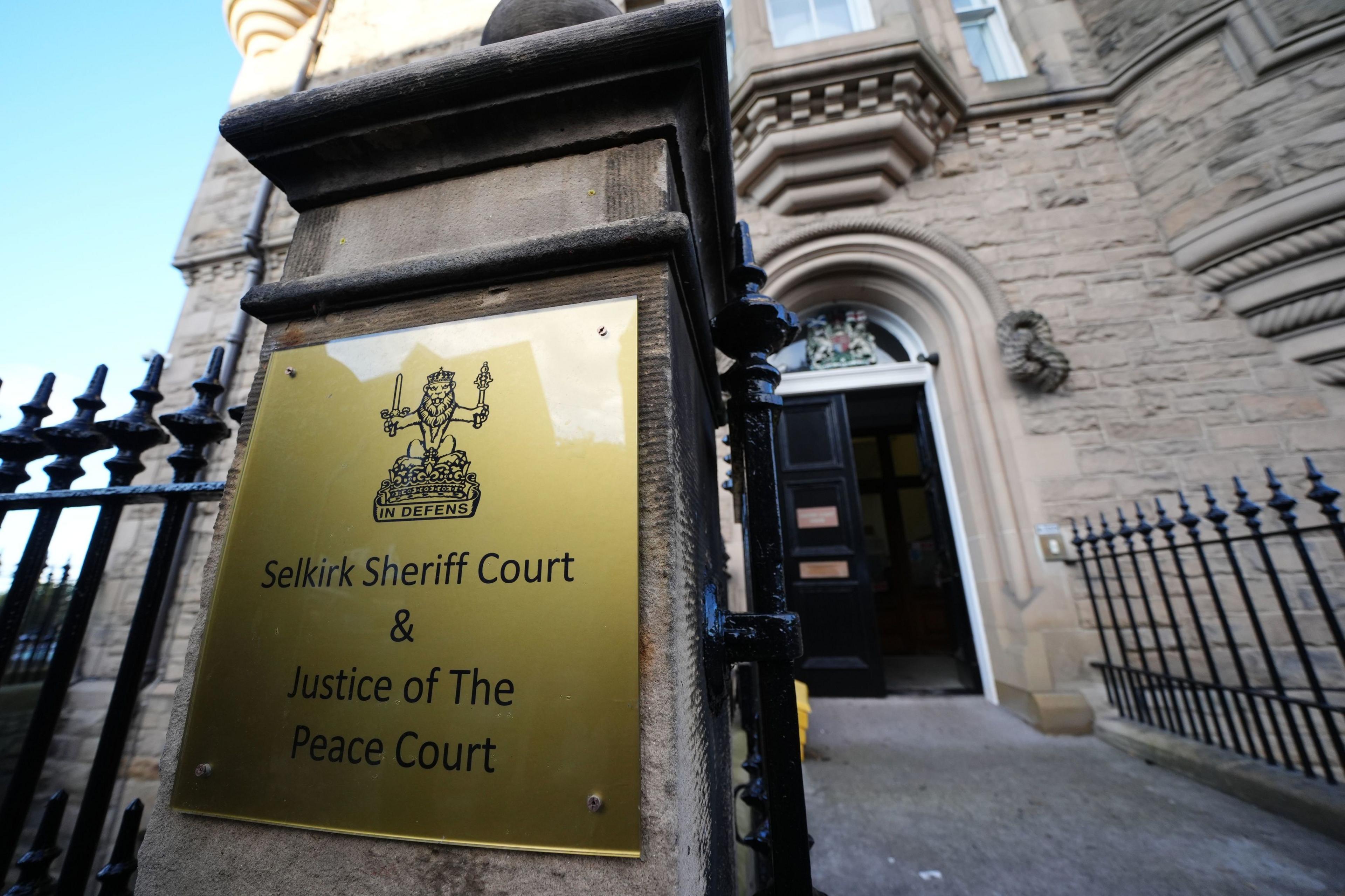 A sign saying Selkirk Sheriff Court and Justice of the Peace Court outside a door to the court building and railings