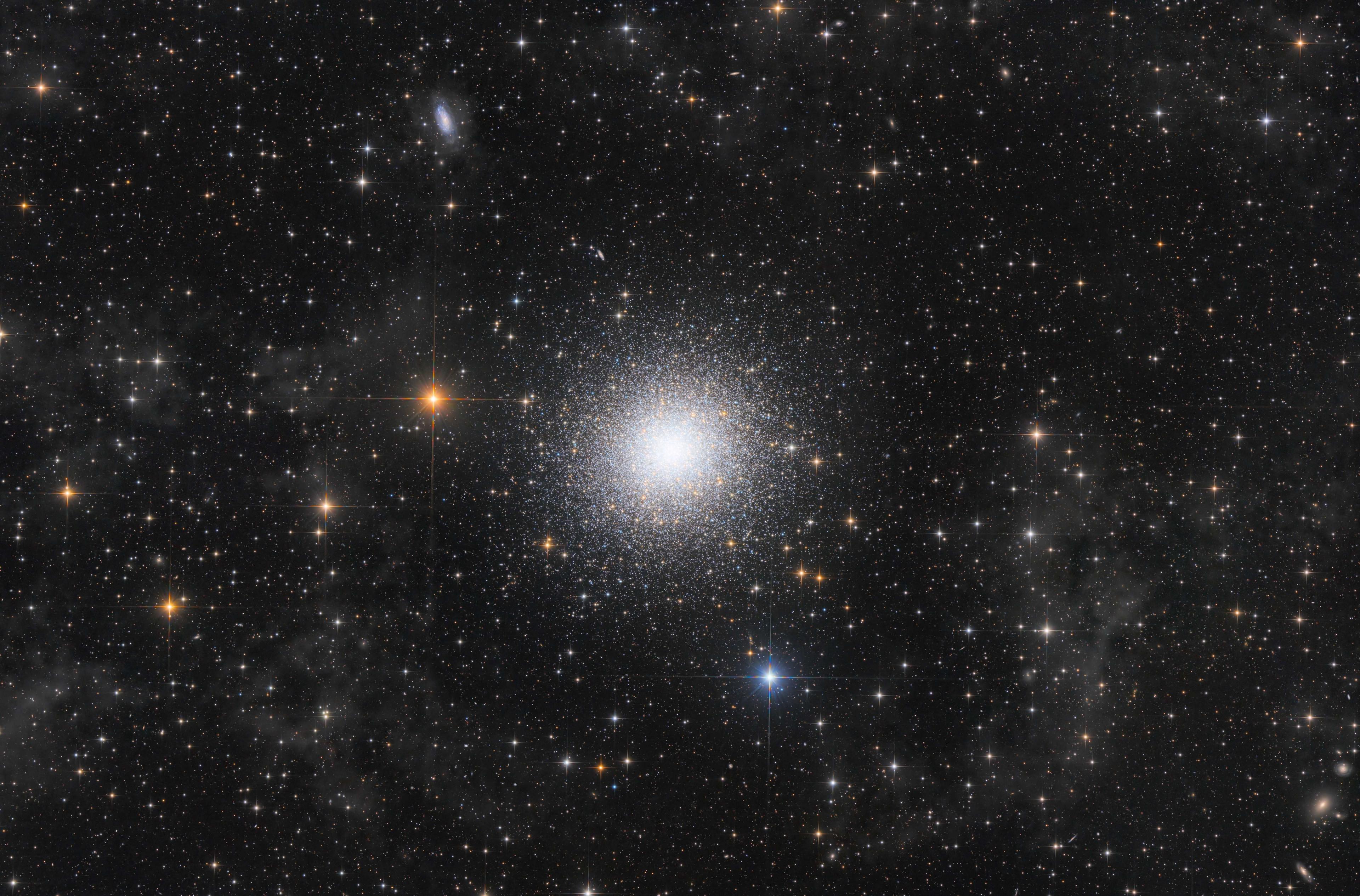 Subtle grey clouds of interstellar dust and a field of local stars make up the foreground. In the middle distance is the Great Hercules Cluster itself, beautifully captured right to its luminescent core. But it’s the background that makes this image complete. Dozens of galaxies pepper the scene.