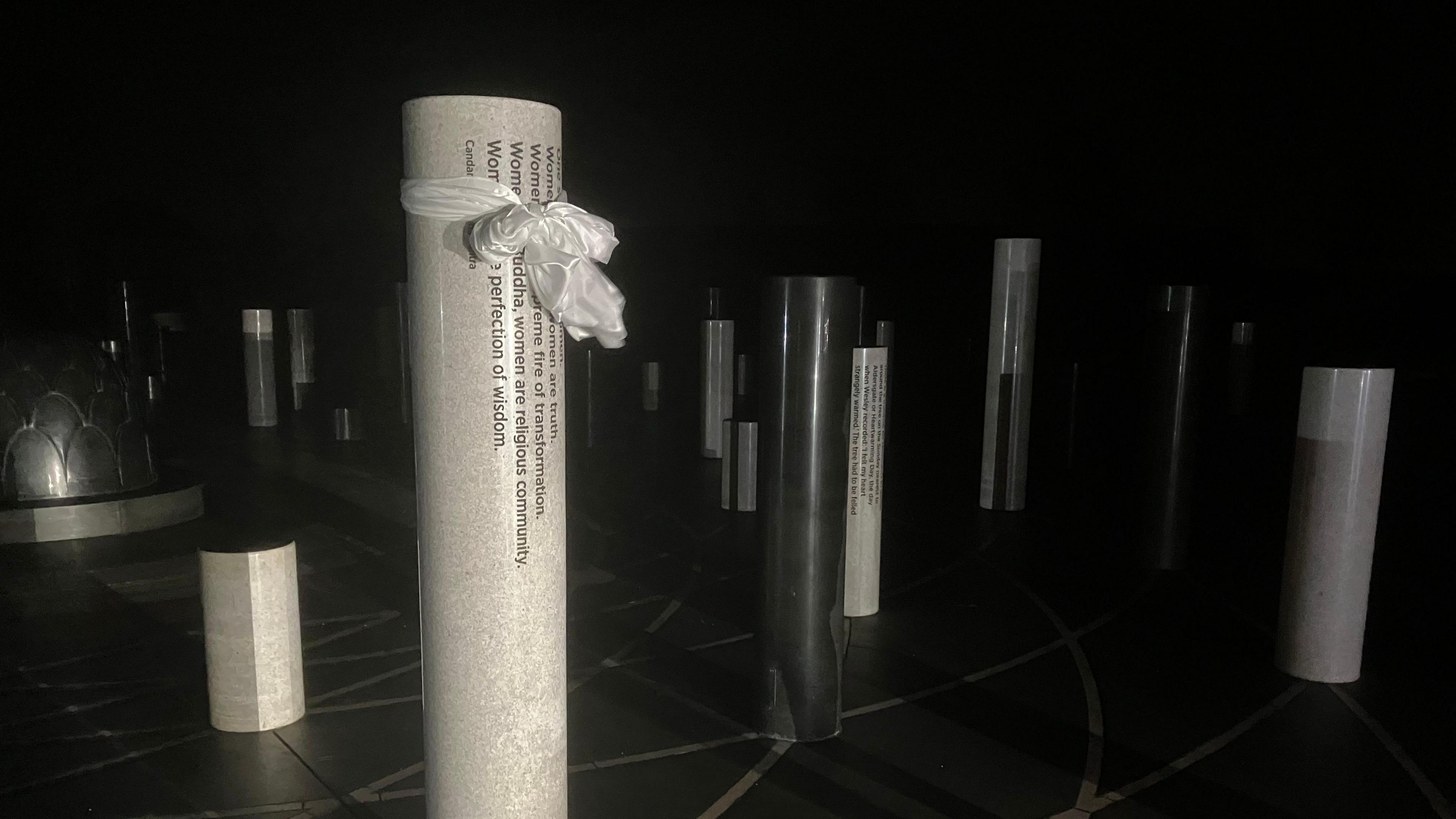 A picture of a white pillar in the dark, with a white ribbon tied to it, to donate white ribbon day.