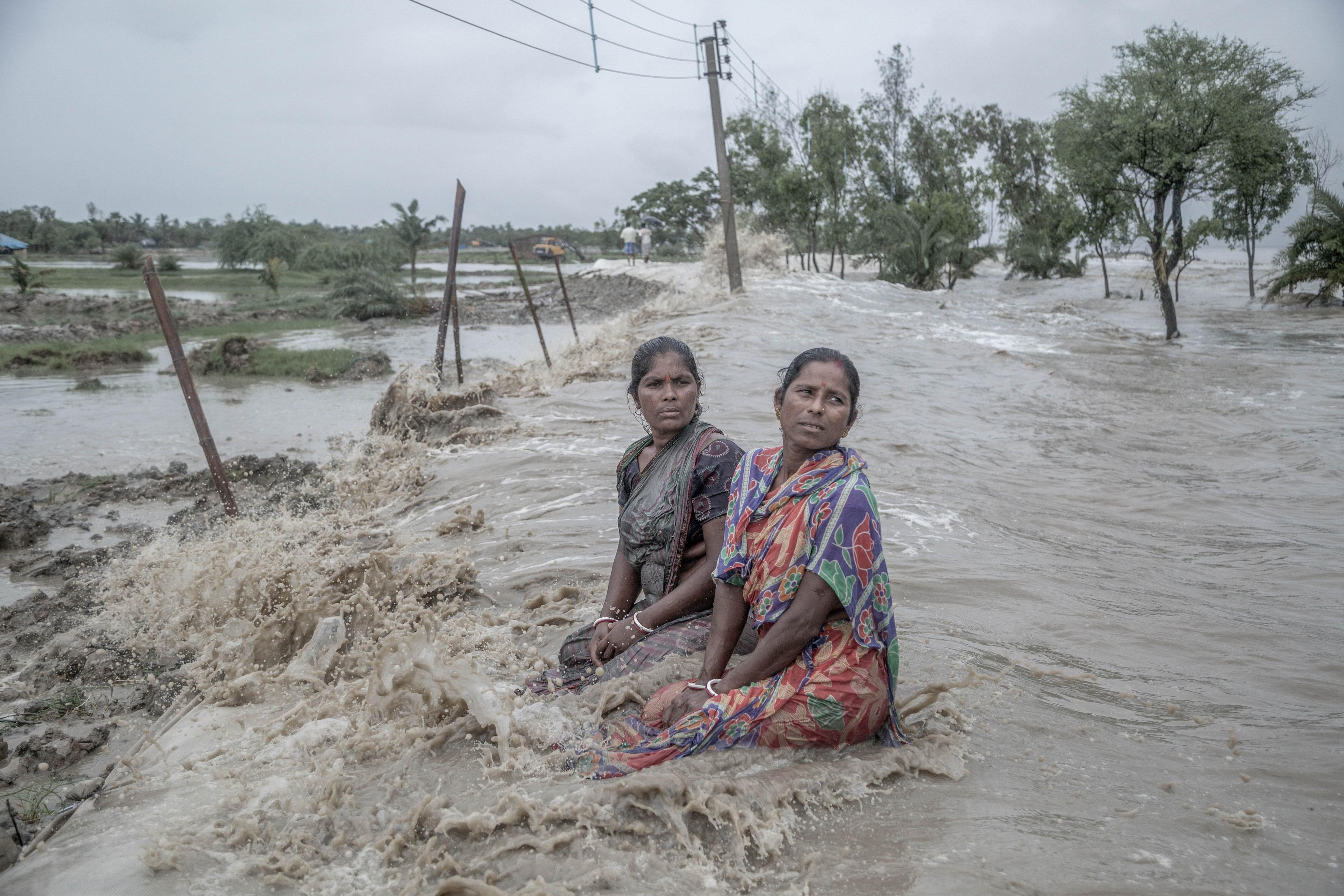 Two women helplessly watch sea waves reclaim their homes in the Sundarbans, India