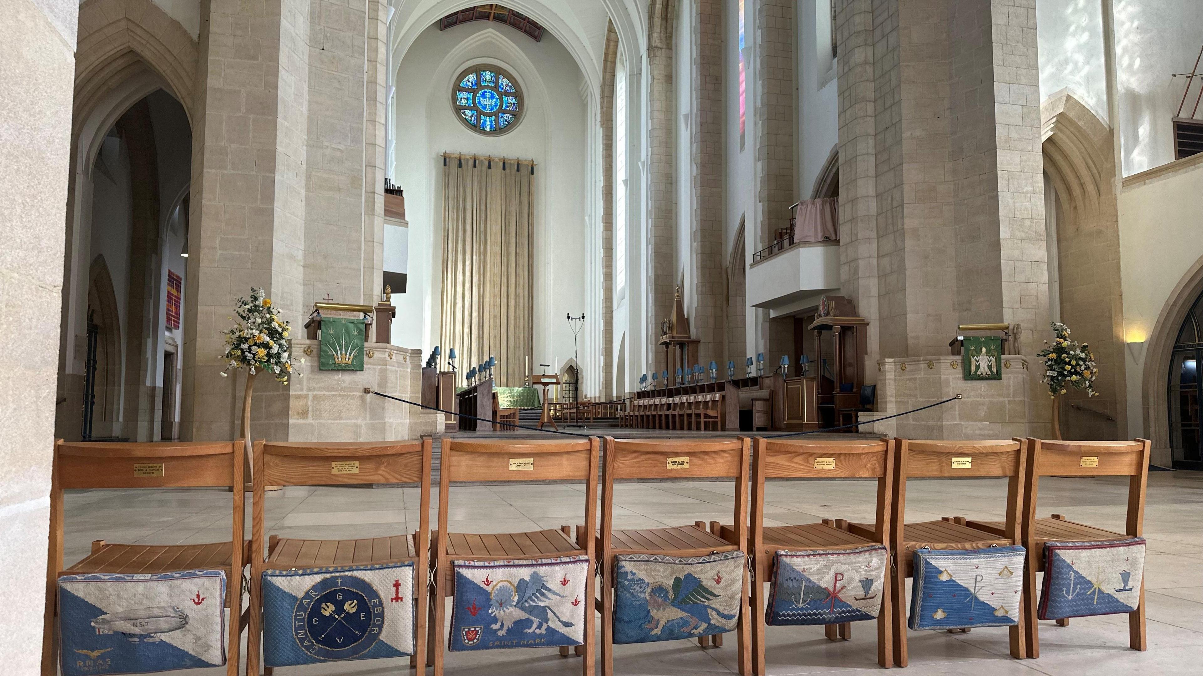 Seven church kneeling cushions hanging off wooden chairs. 