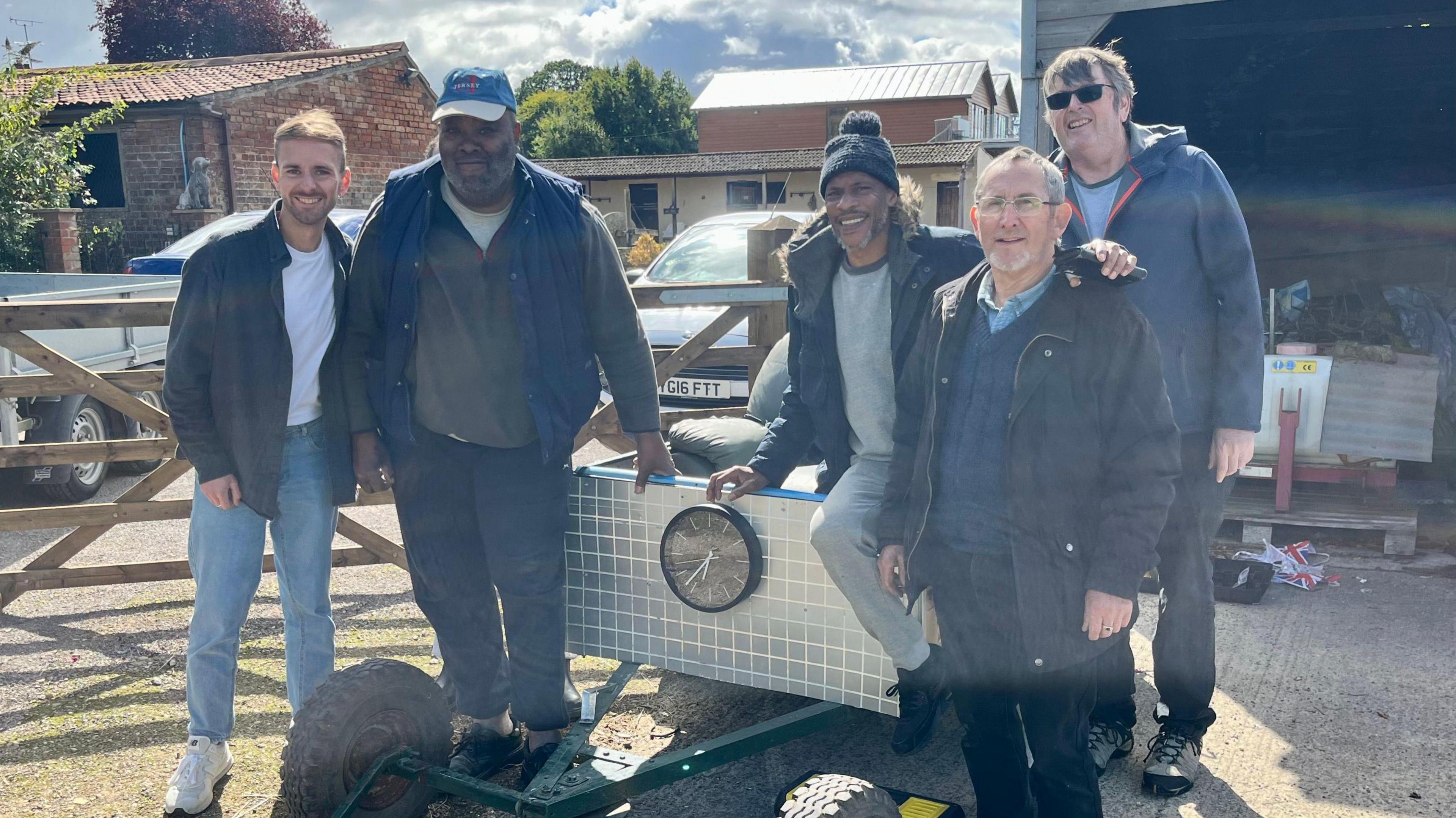 Breakfast presenter Jon Smith and members of the Matson Community Shed are pictured smiling sat on an old soapbox.