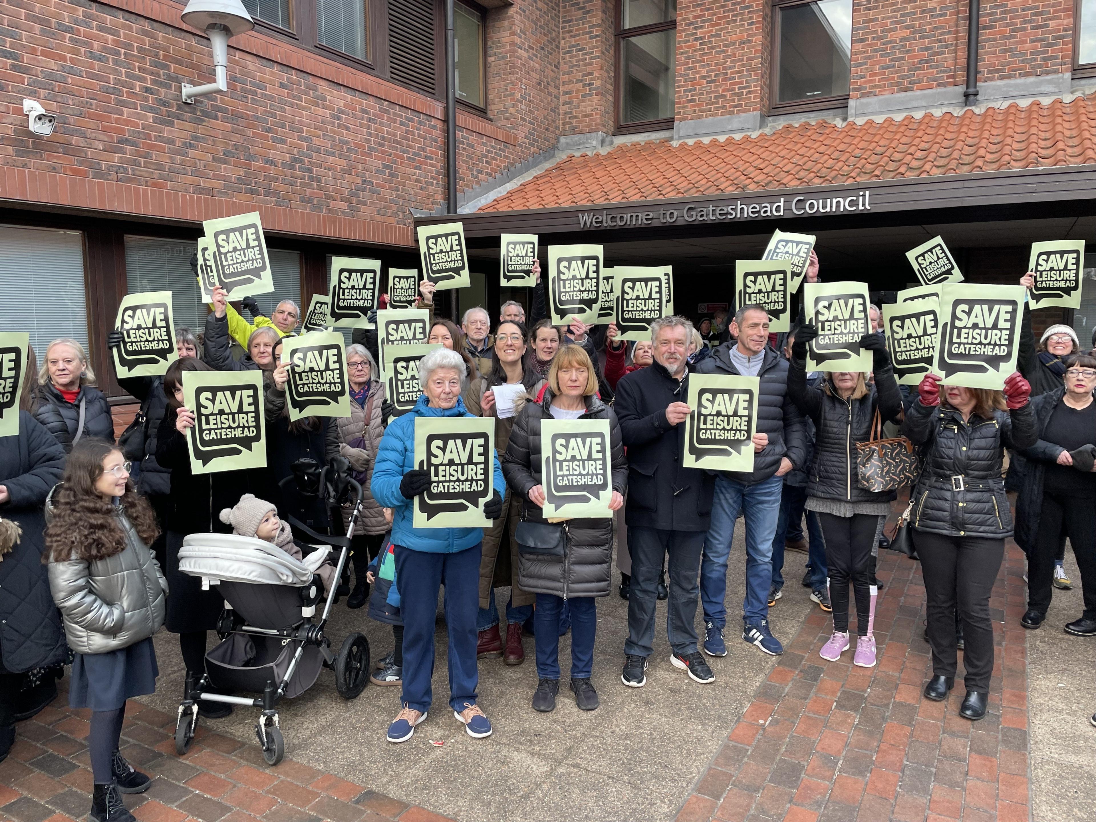 Protestors holding Save Leisure Gateshead placards stand outside the offices of Gateshead Council.