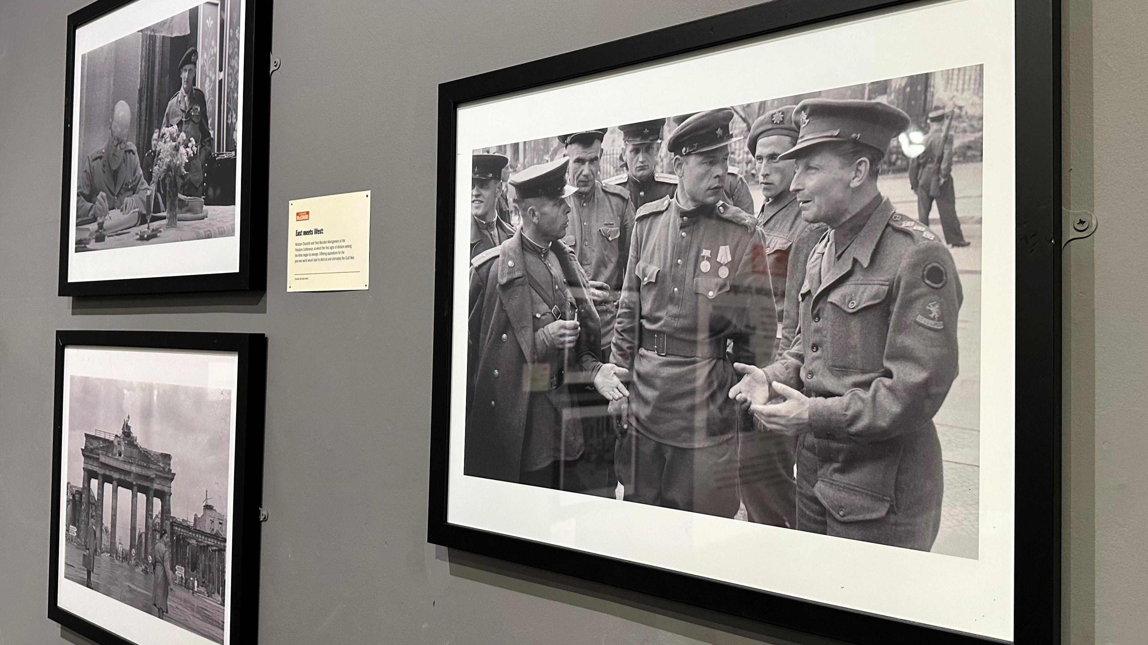 There framed photos on a wall with the largest featuring British and Russian soldiers in conversation.