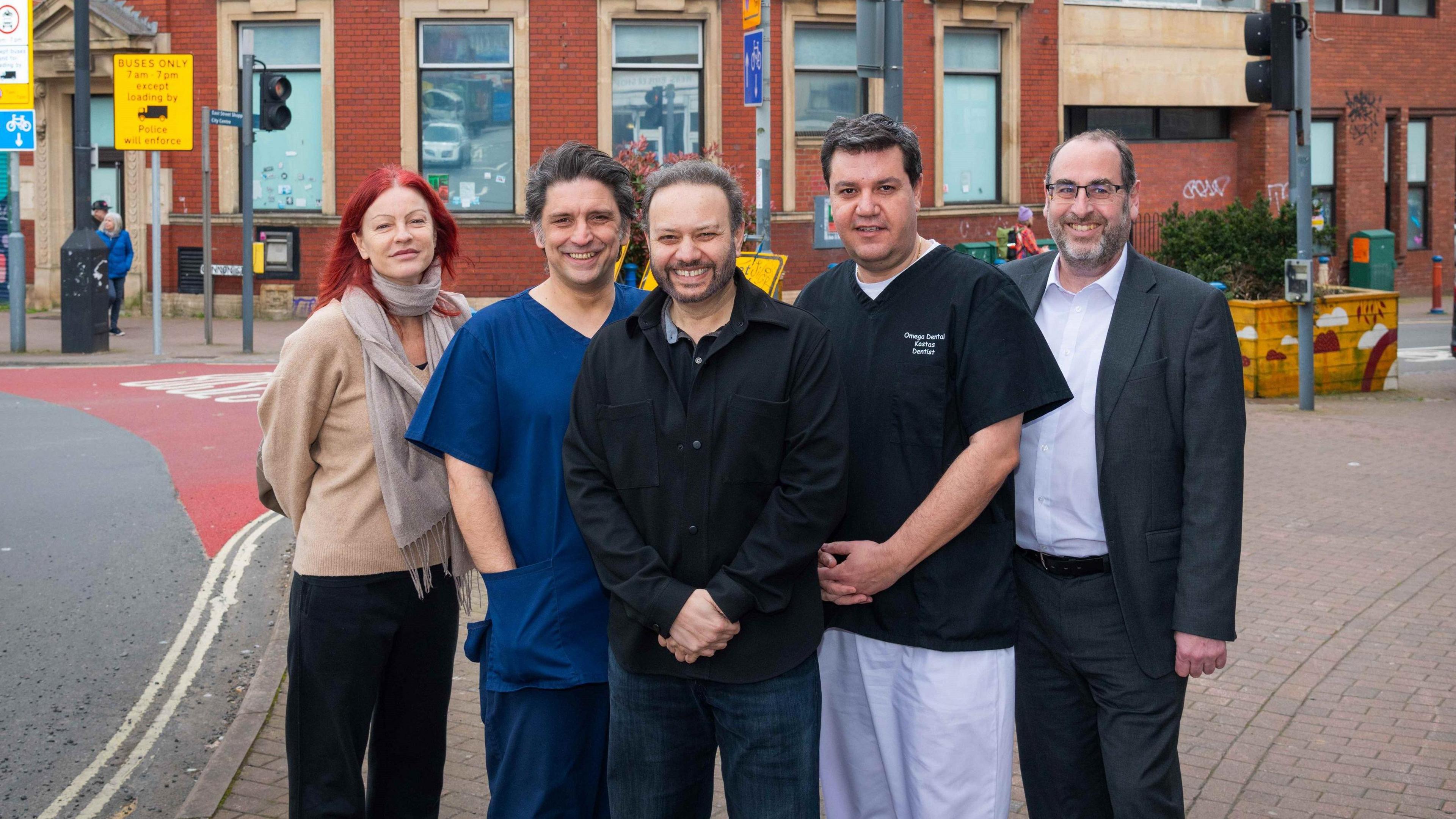 A group of people including local councillor Tony Dyer stand on the corner of Cannon Street and East Street in Bedminster to announce the opening of a new dentists. They are smiling at the camera.