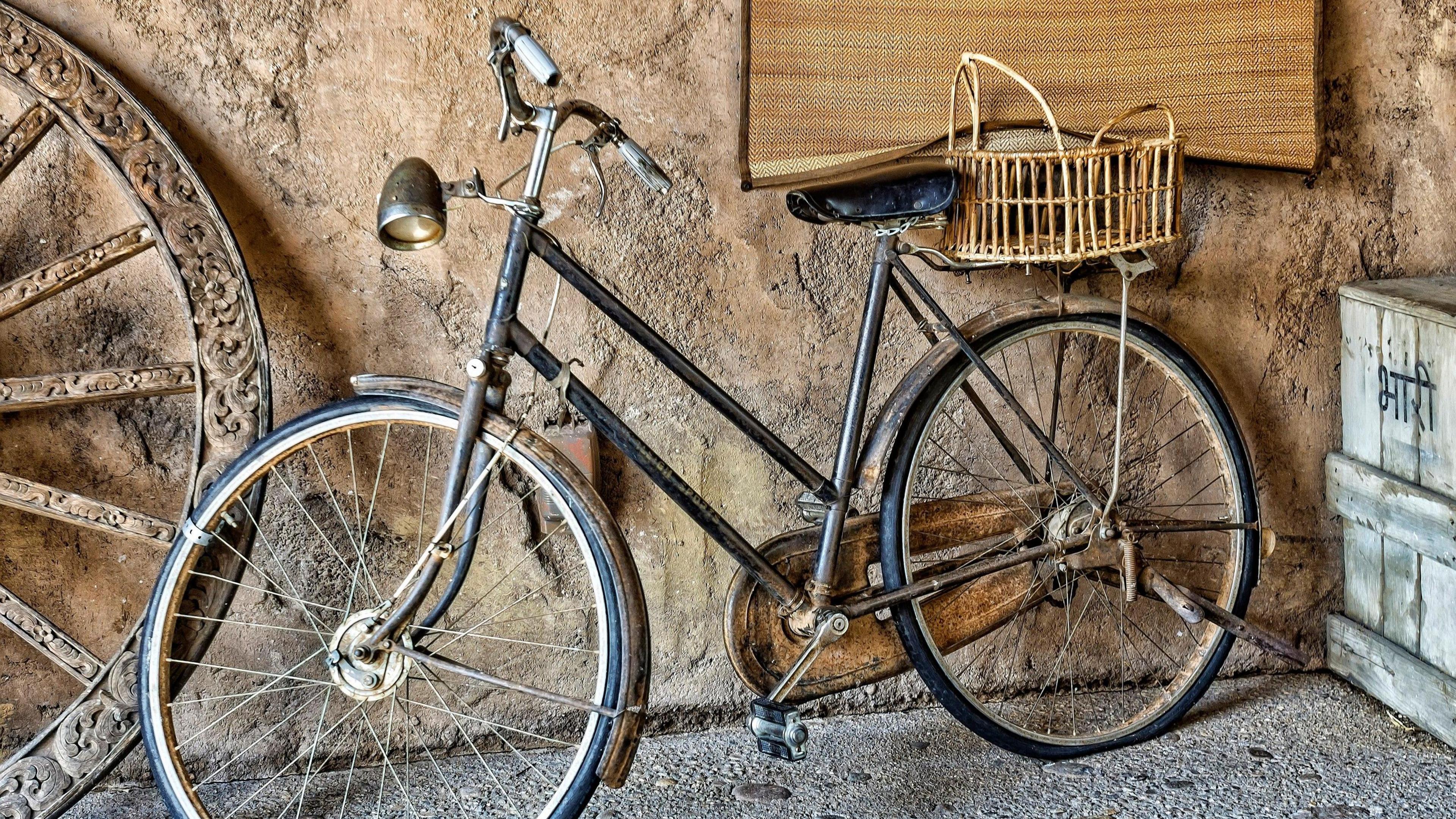 A beaten up old bike resting against a wall in a garage.