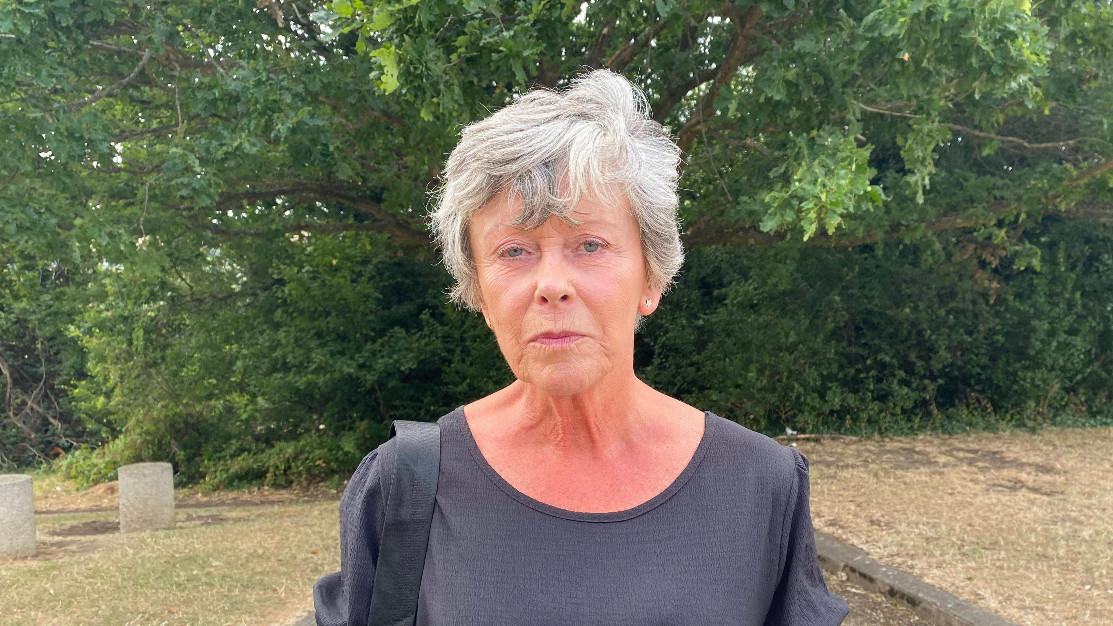 An elderly woman. She has short grey hair. 