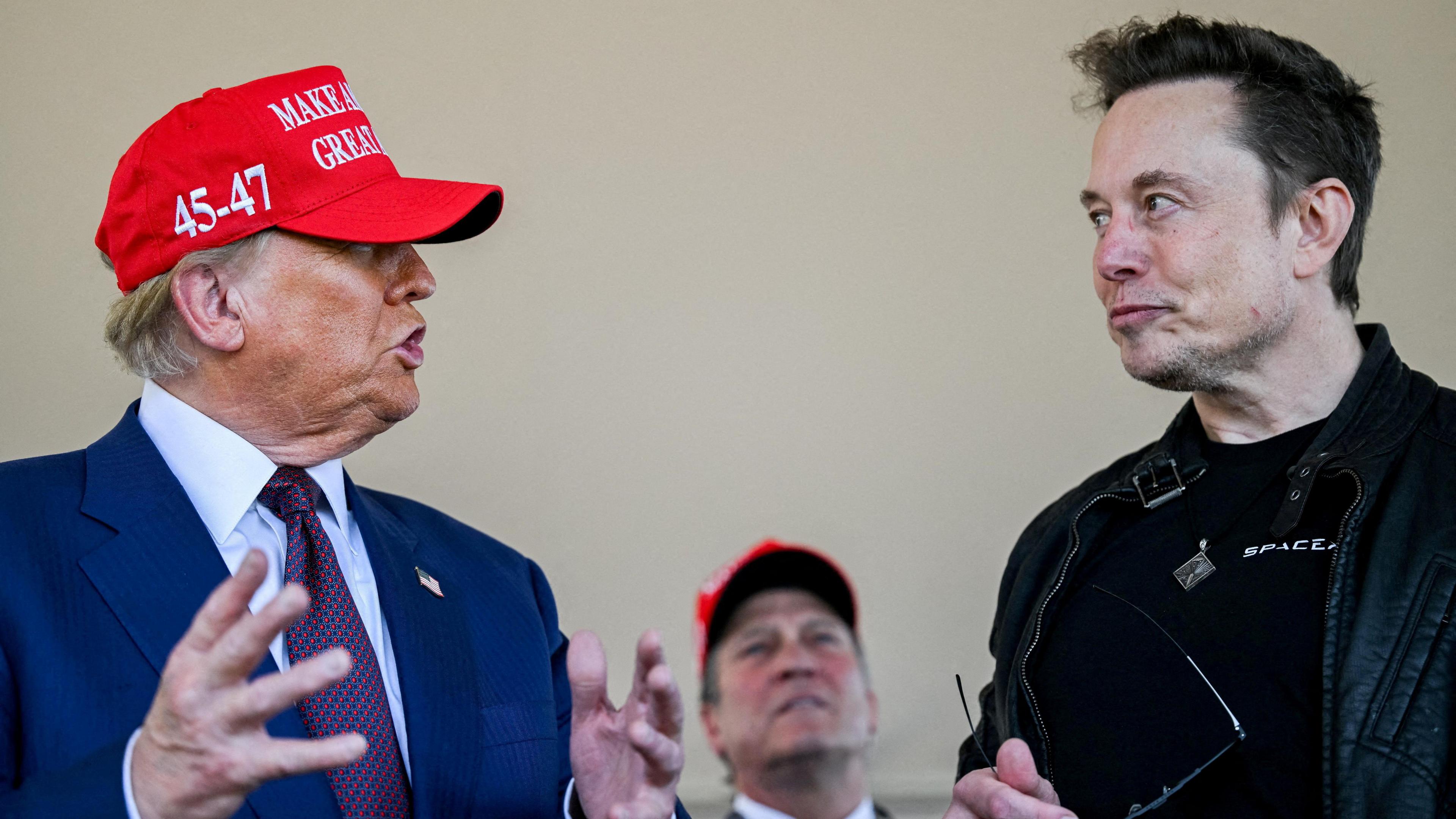 Elon Musk wearing a leather jacket listens during a conversation with US President-elect Donald Trump, wearing a suit and a baseball cap, at a viewing of the launch of the sixth test flight of the SpaceX Starship rocket