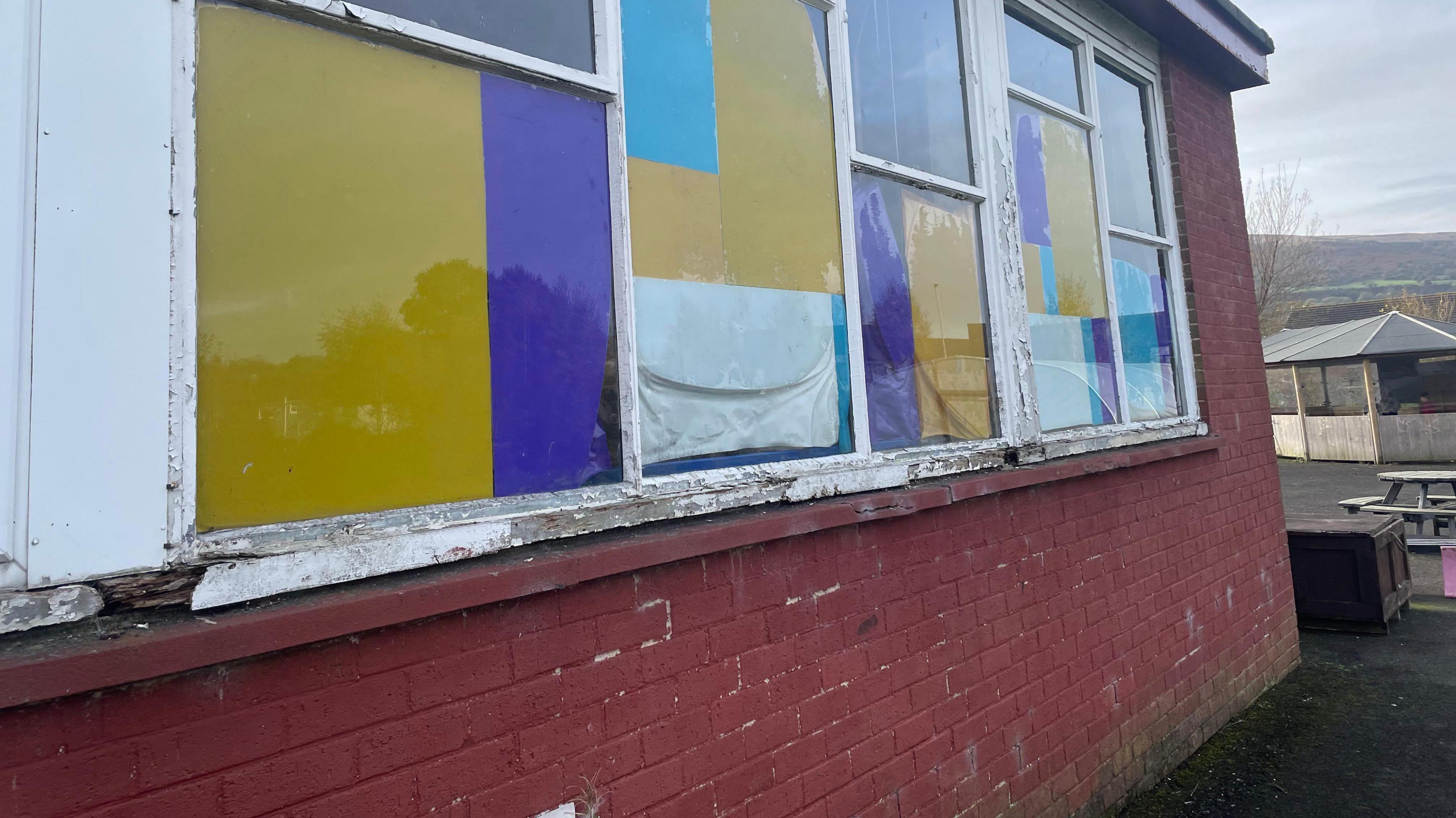 A window frame rotted away on a red brick wall.
