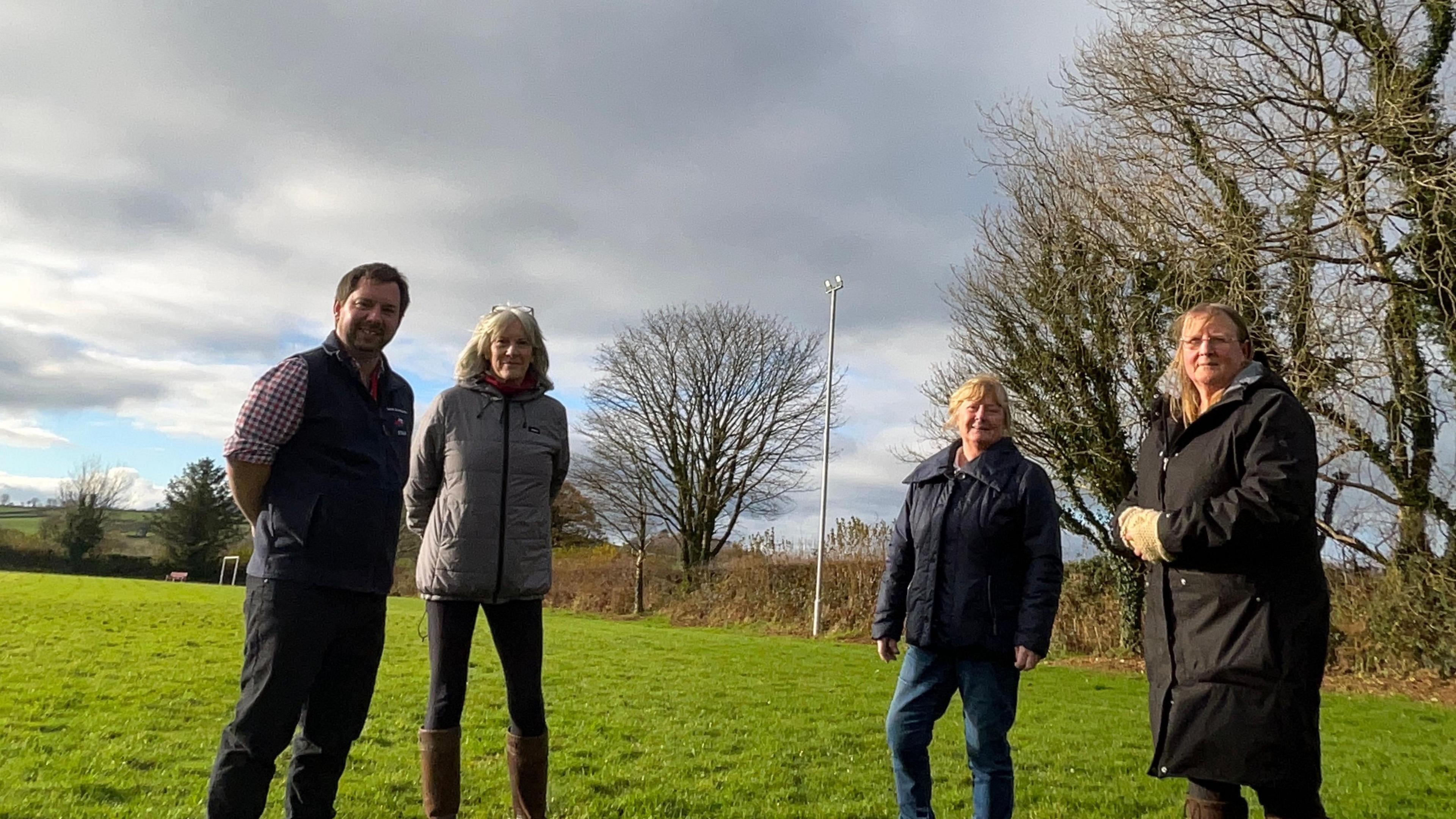 Four people stand outside at the new air ambulance landing site in a playing field