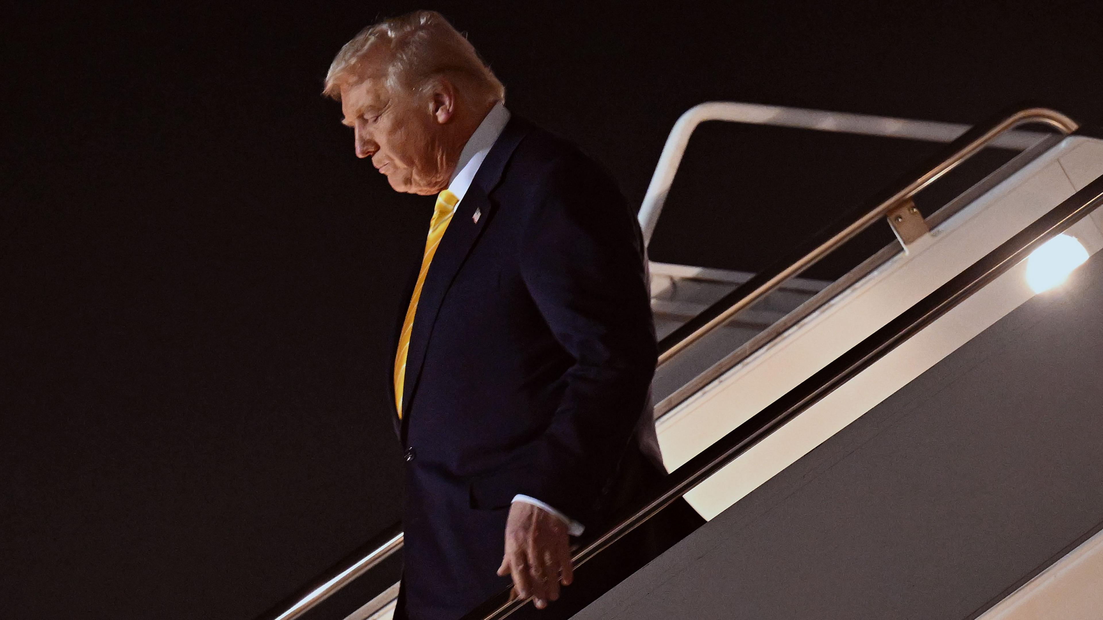 Donald Trump walking down steps of Air Force One, looking downwards