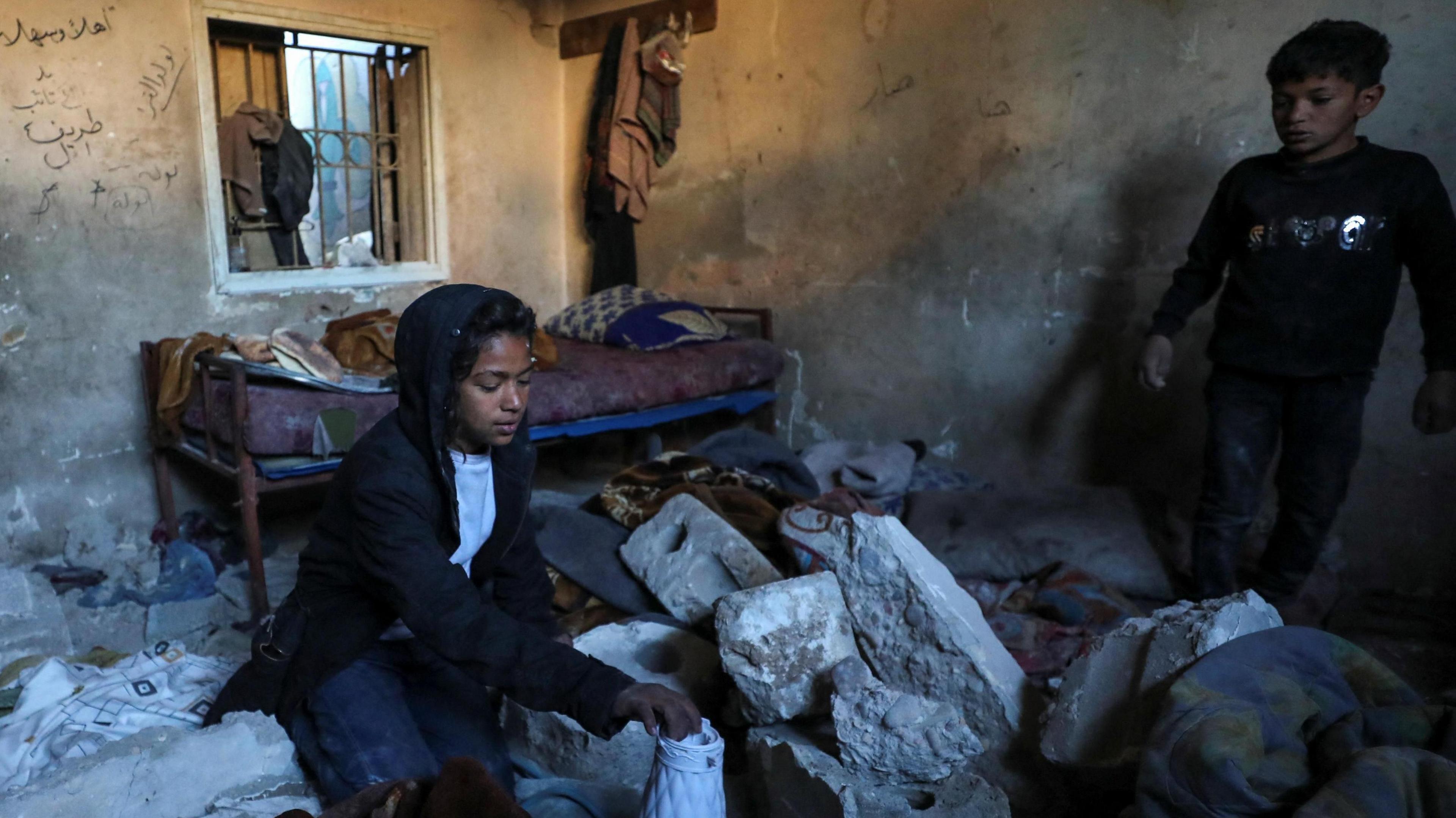 Palestinians search for their belongings inside a school sheltering displaced people after it was hit by an Israeli strike, in Gaza City, northern Gaza (13 January 2025)