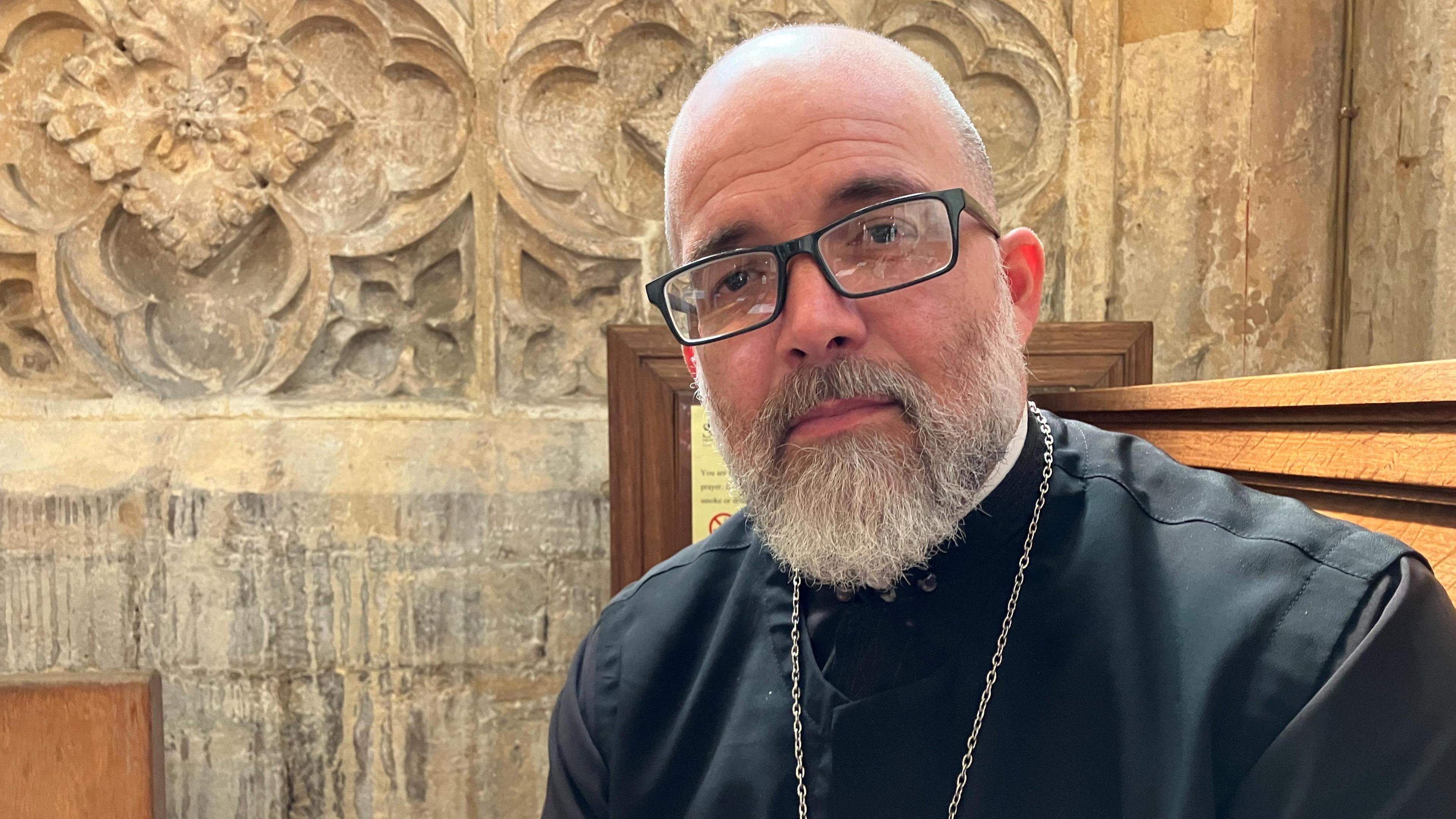 Father Juan Carballosa sits in a church