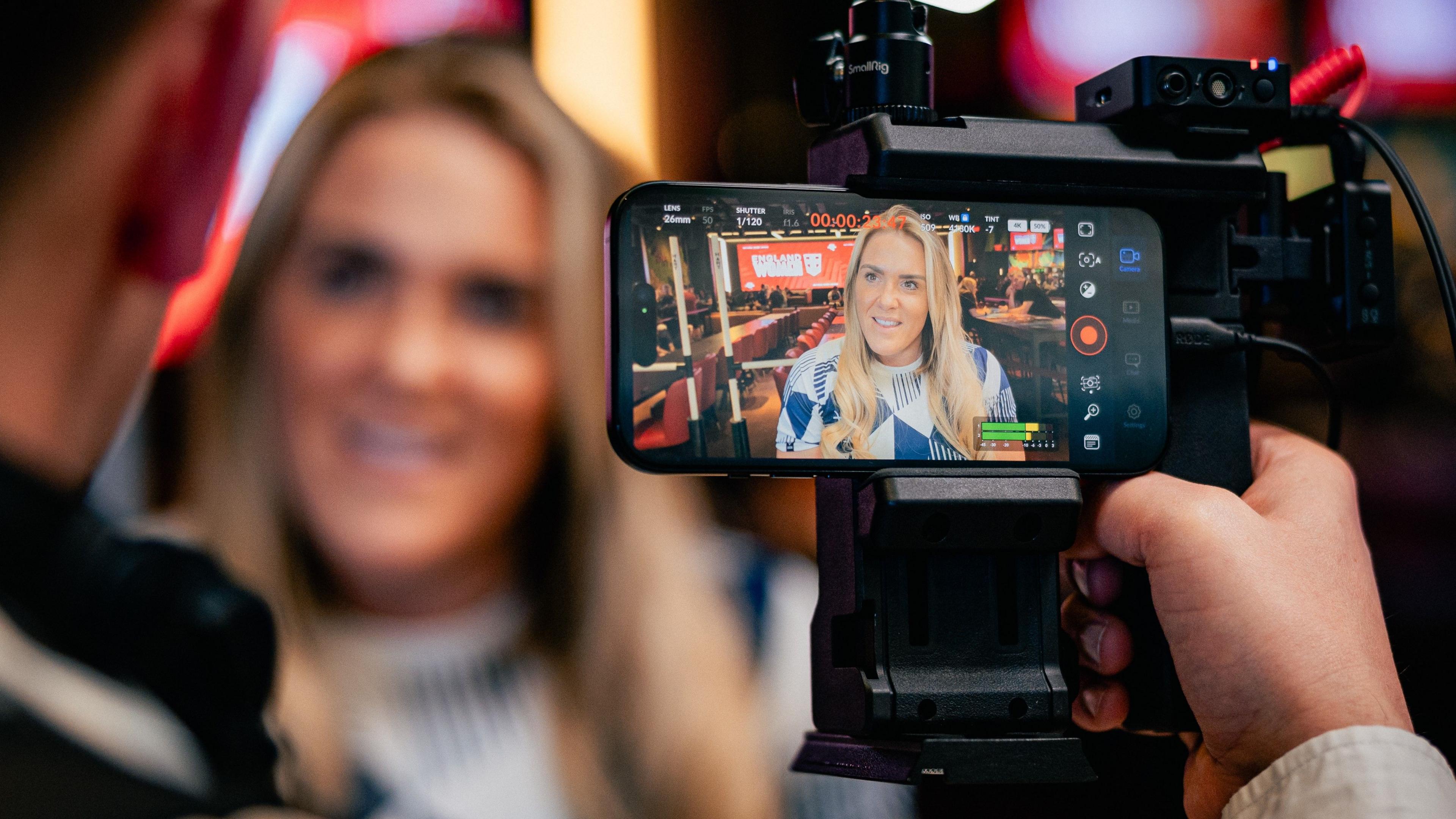 Amy Hardcastle as seen through a camera viewfinder, giving an interview