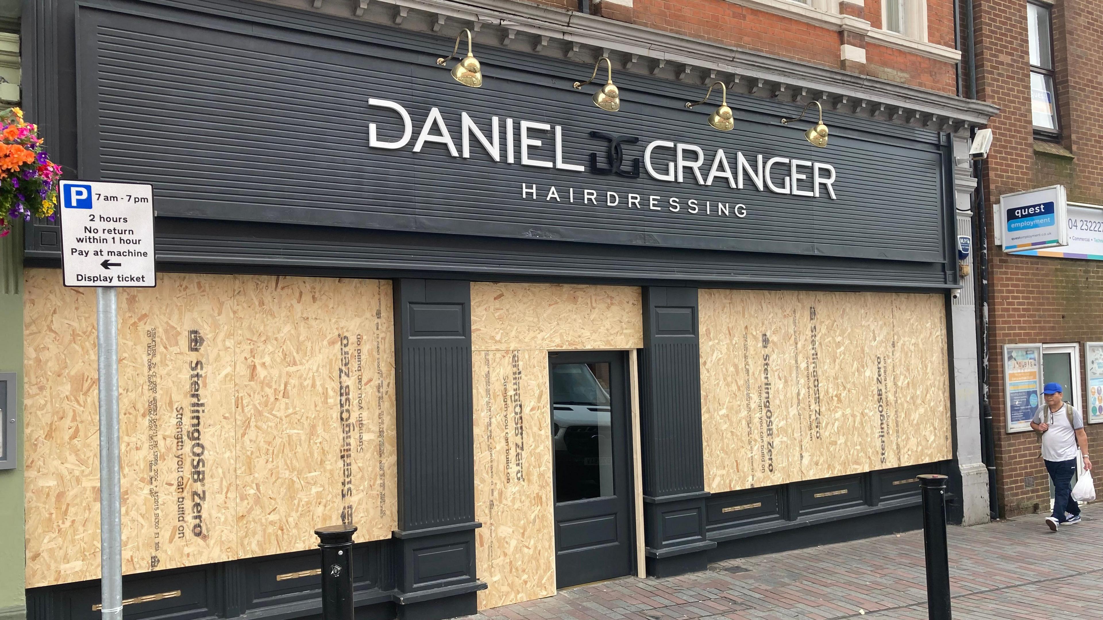 A salon front has boards placed over its windows