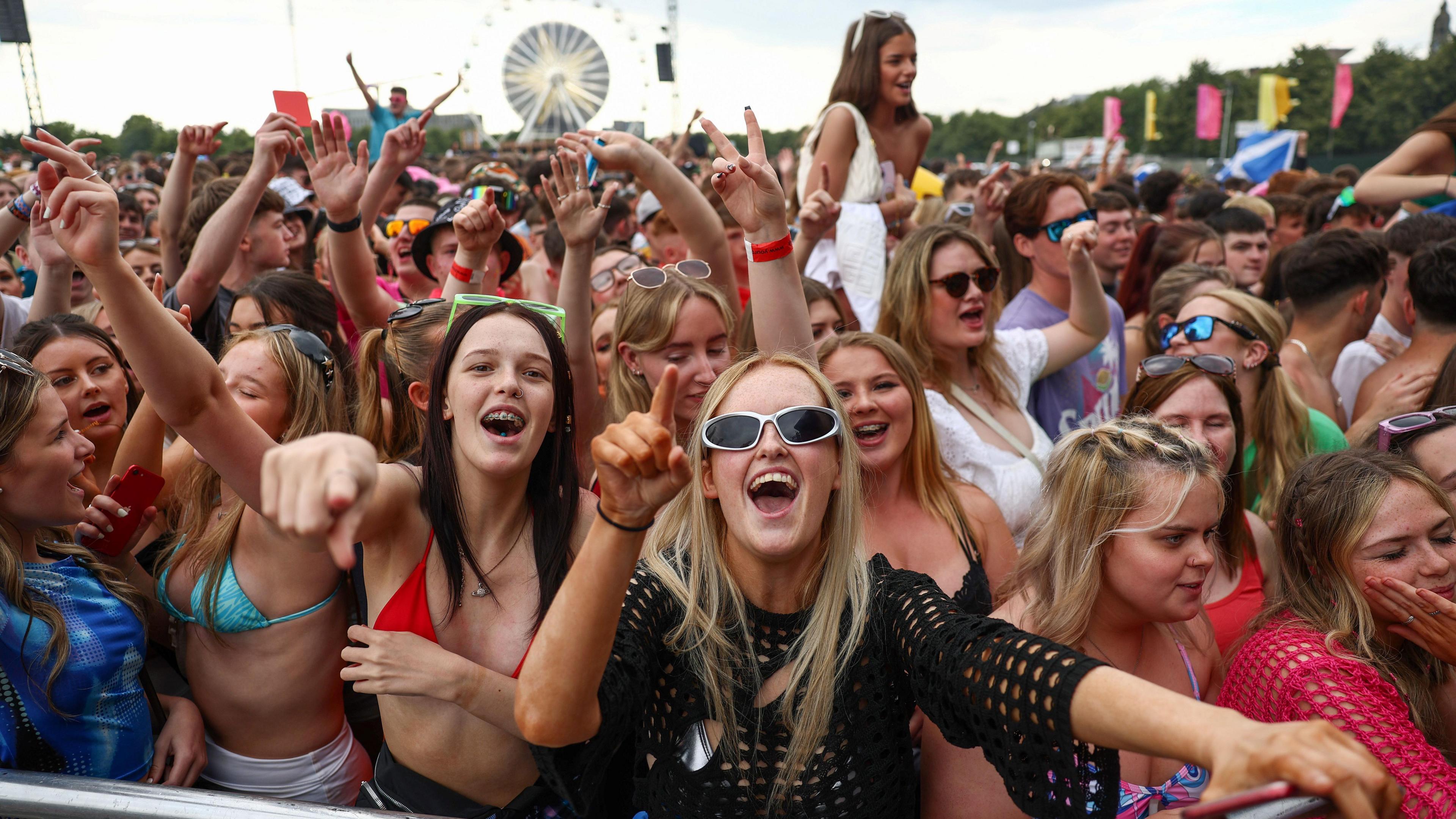 A cheering crowd at the TRNSMT music festival. Many are singing along or have their arms in the air.