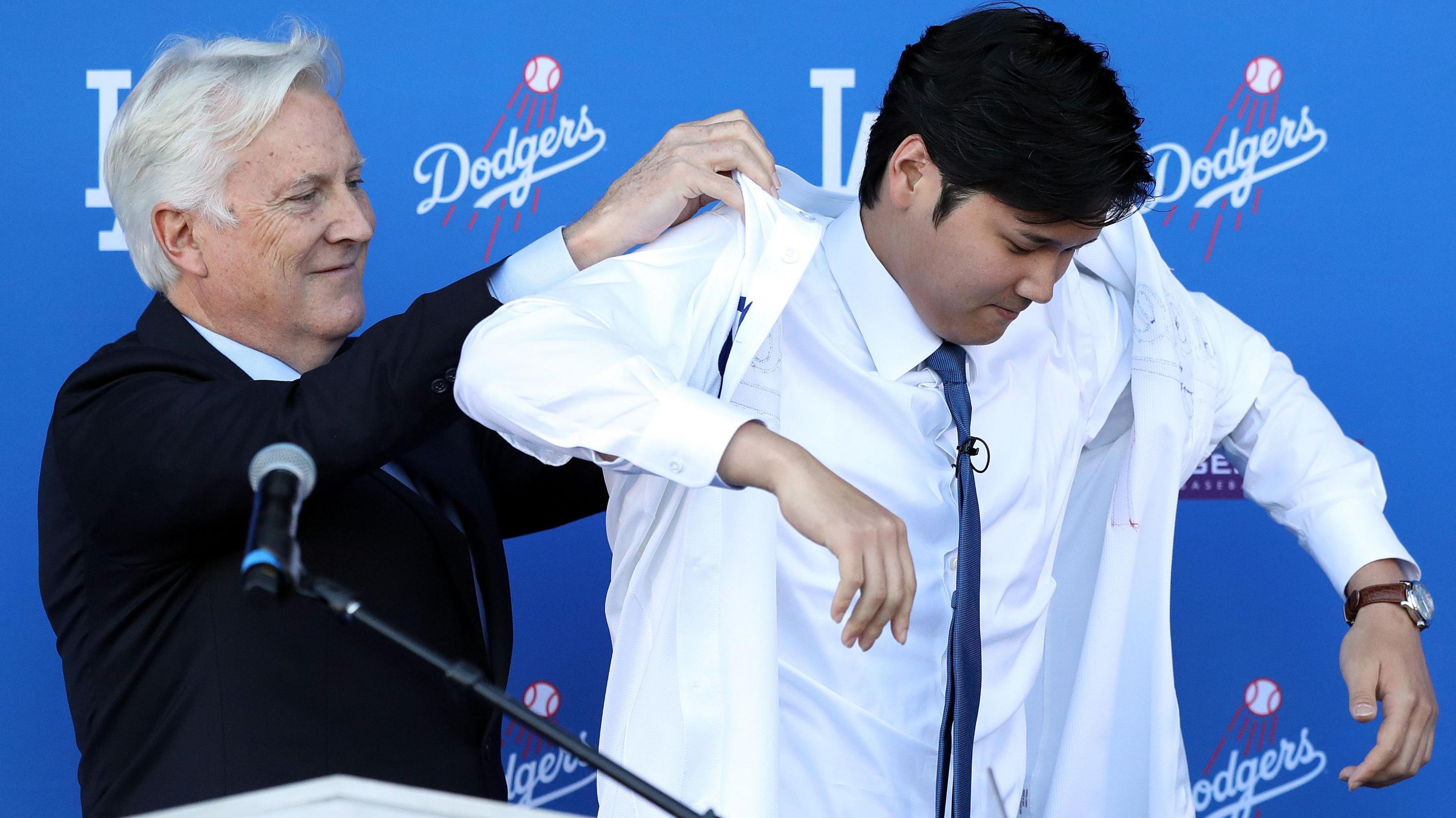 Mark Walter puts a shirt on baseball star Shohei Ohtani