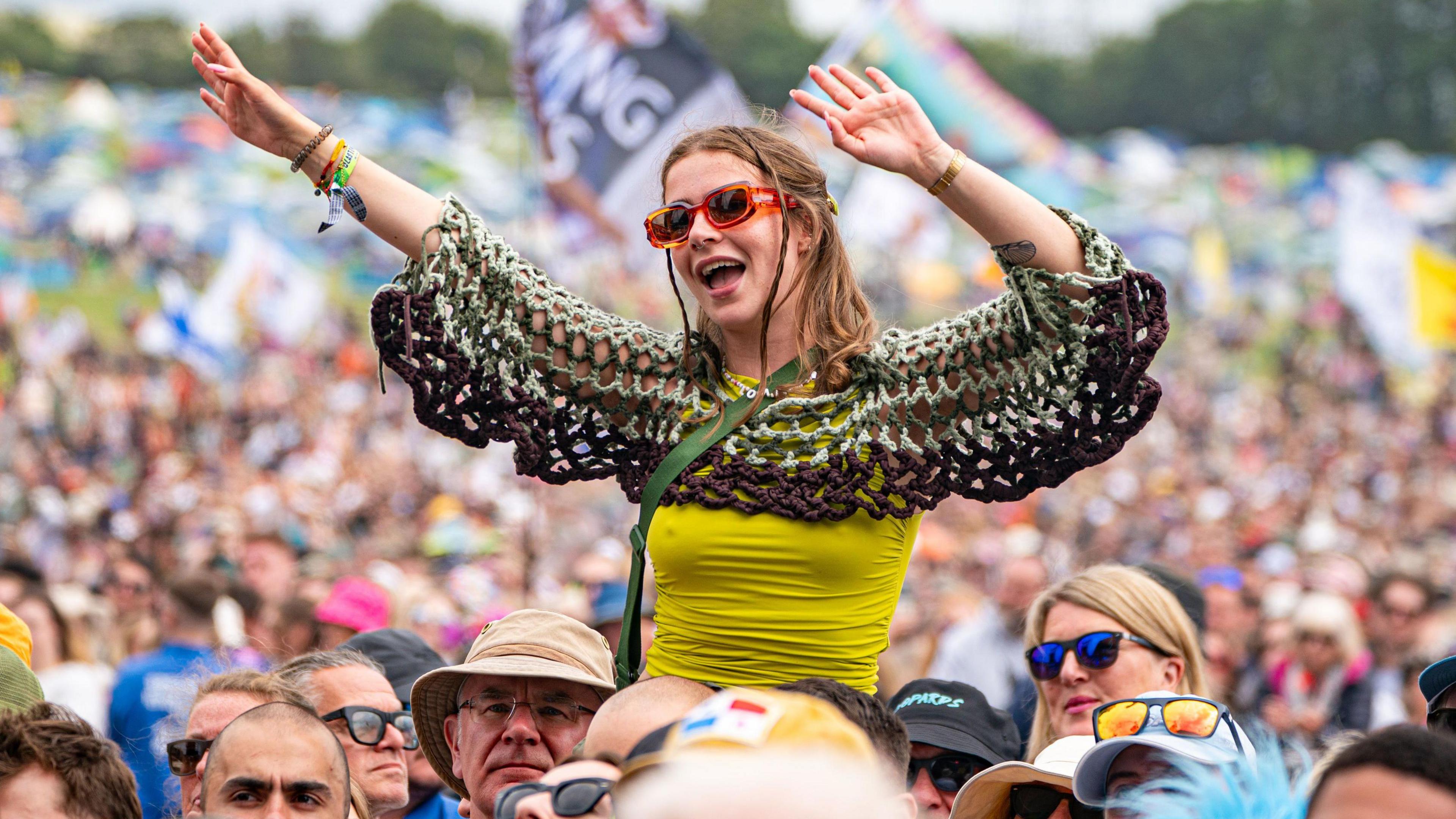 A girl stitting on someone's shoulders at a festival