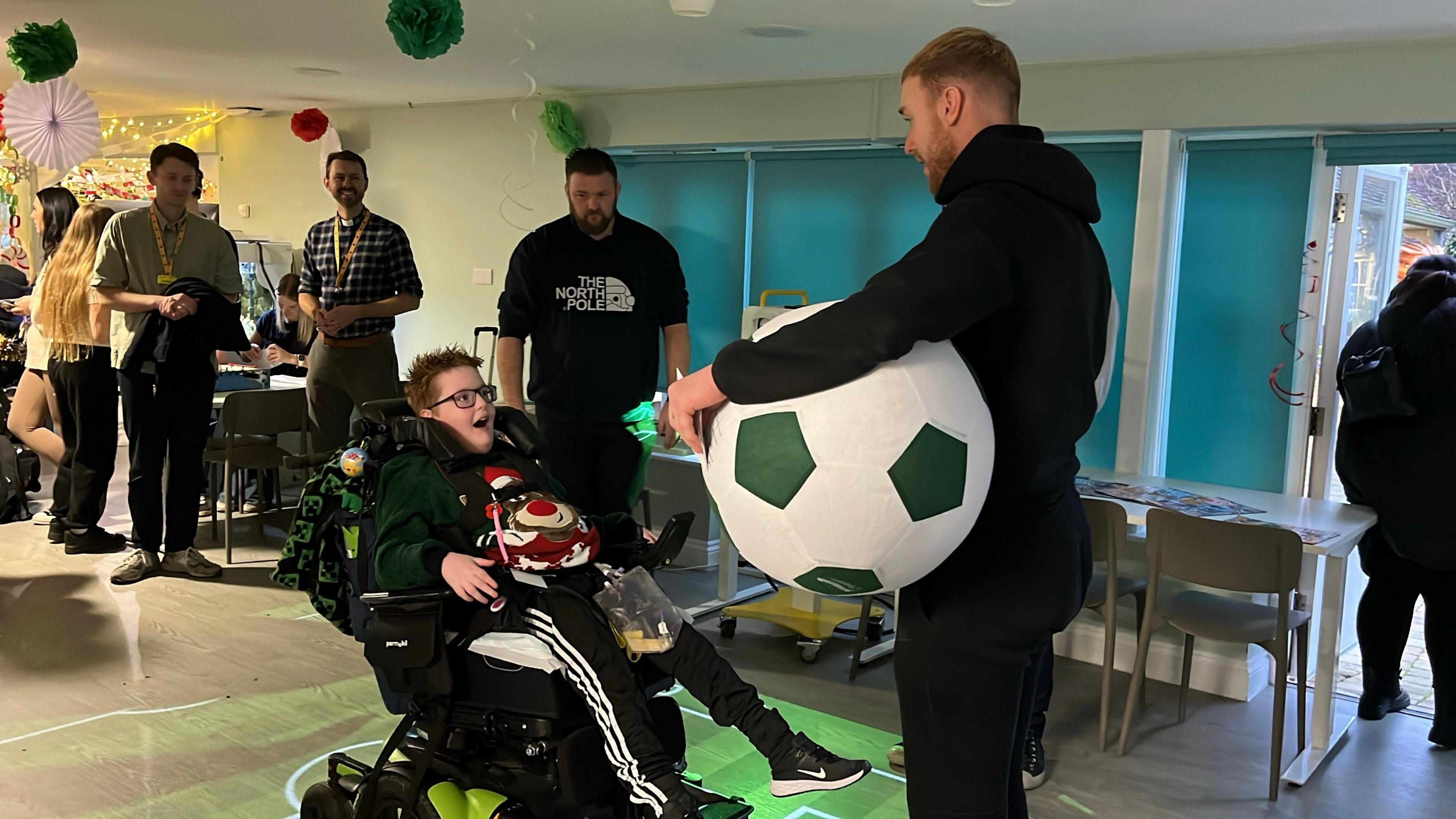 Jacob standing opposite men's keeper JAson Steele who is holding a large football